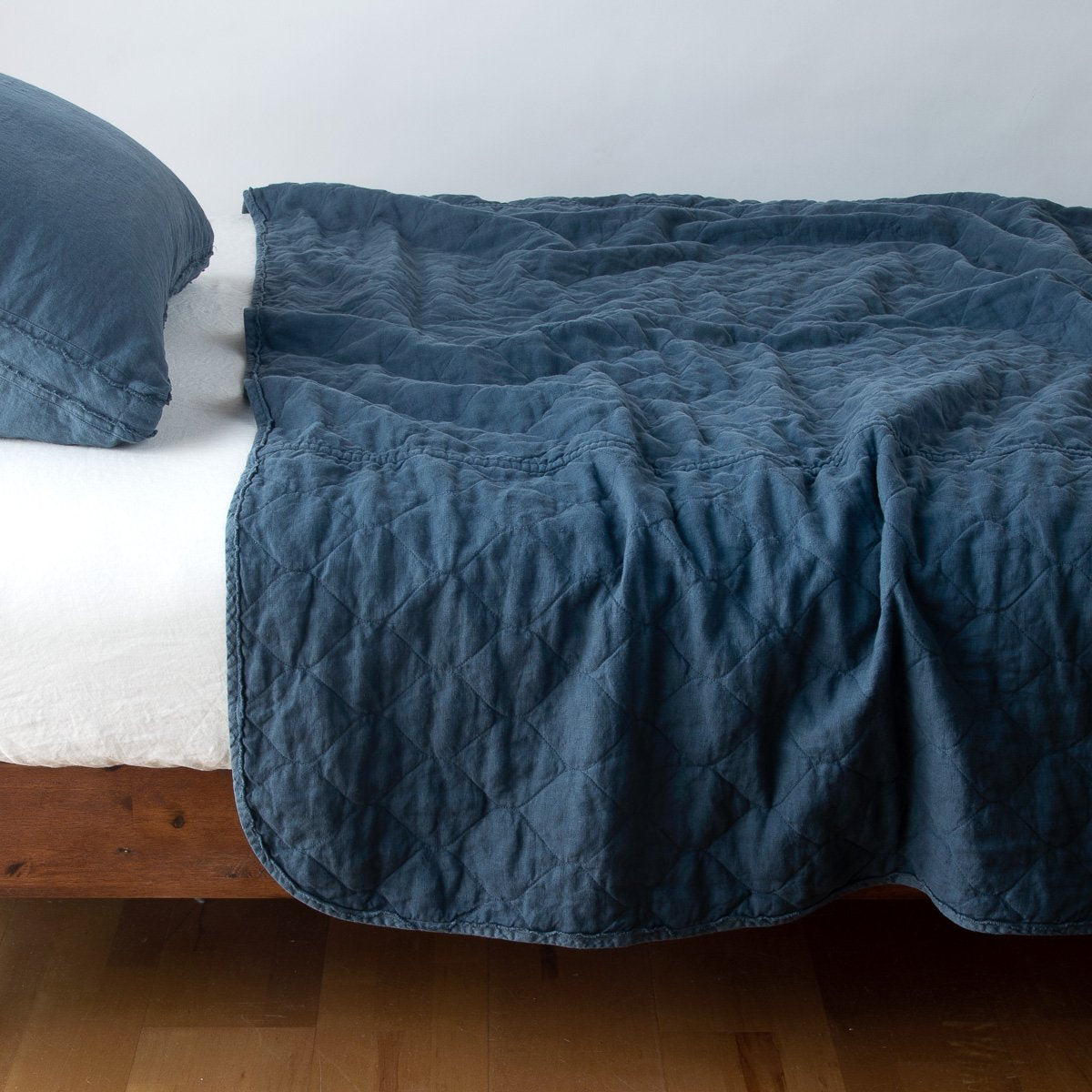 Midnight: quilted midweight linen coverlet on a bed - side view.'