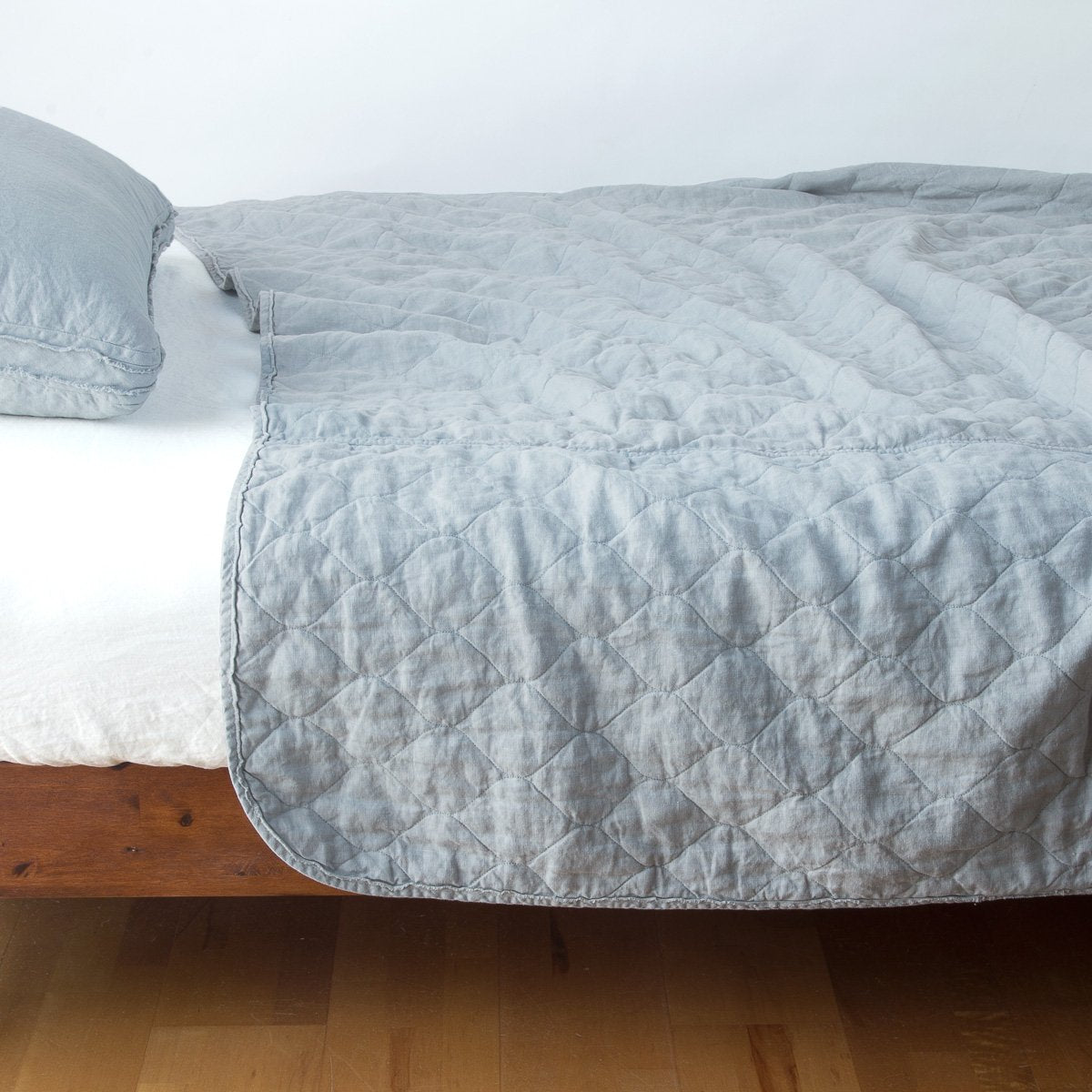 Mineral: quilted midweight linen coverlet on a bed - side view.