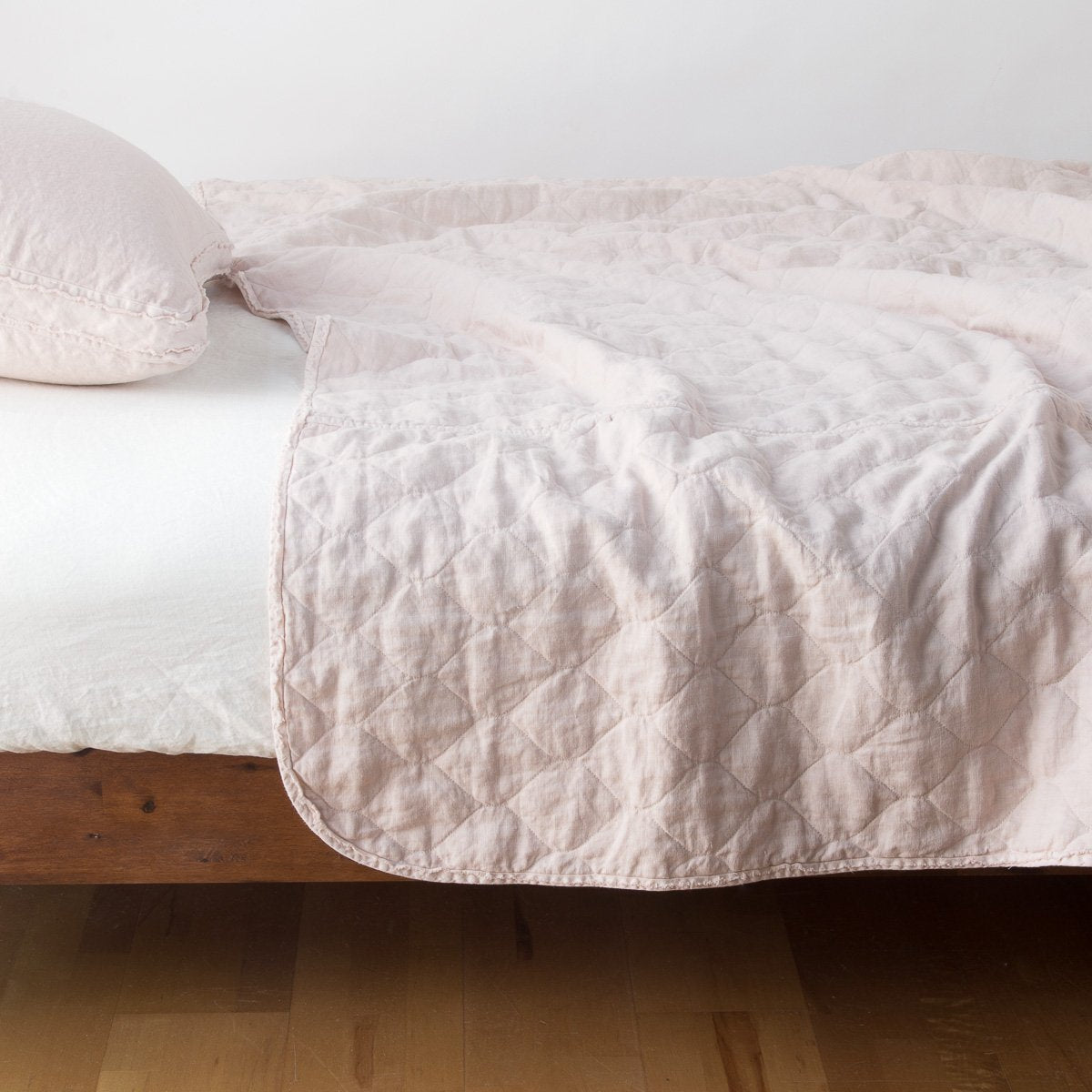 Pearl: quilted midweight linen coverlet on a bed - side view.