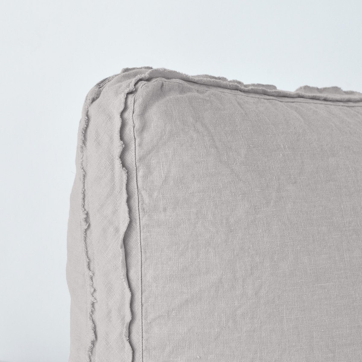 : Close up angle of the corner of an Austin sham in fog, highlighting the raw edge trim on either side of the gusset.