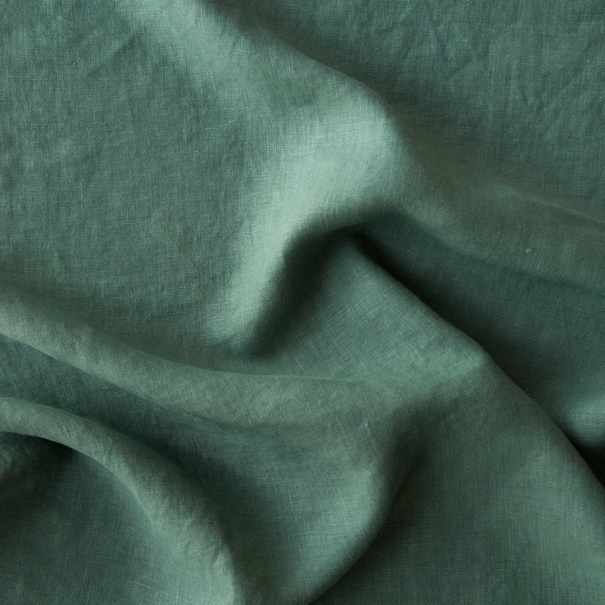 Jade: A close up of midweight linen in jade, a rich, verdant green with subtle blue undertones.
