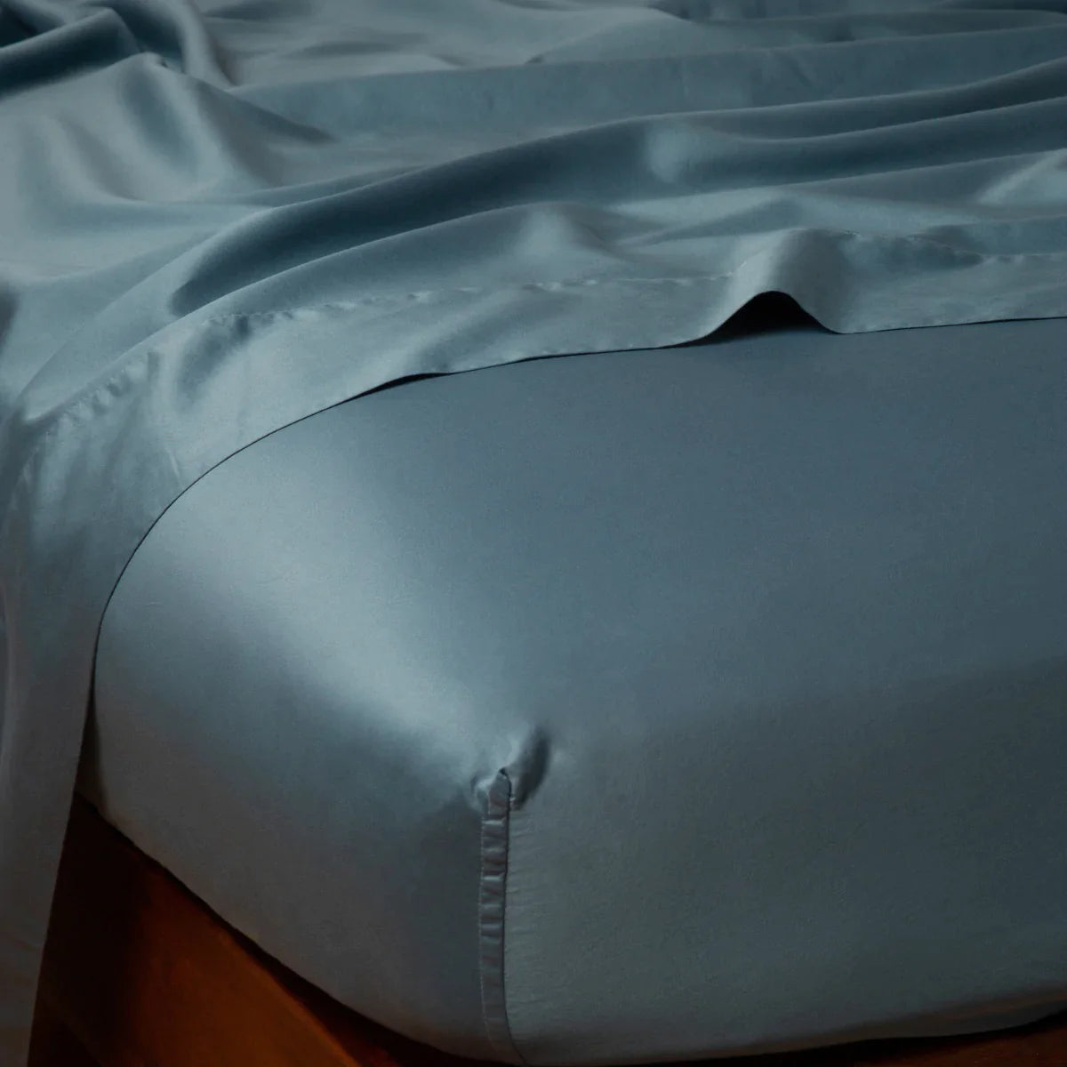 Cenote: Cotton sateen fitted sheet shown from the top corner, highlighting the shine of the fabric.