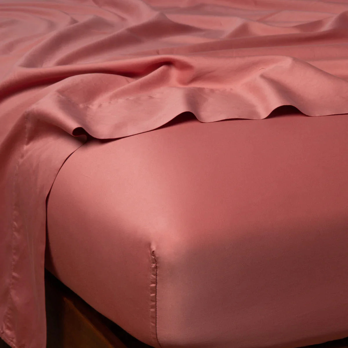 : Bria fitted sheet in poppy shown from the top corner, highlighting the shine of the cotton sateen.