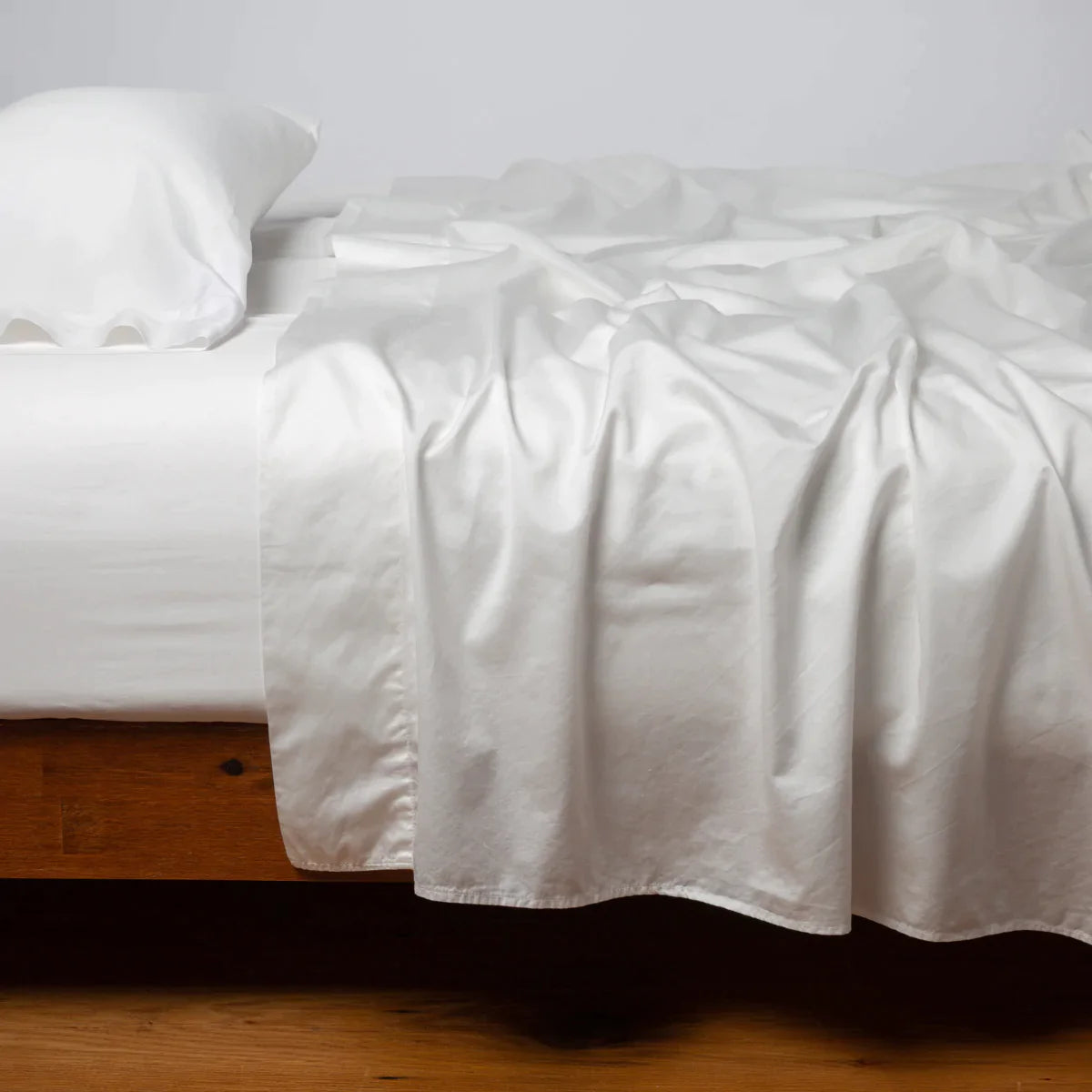 Winter White: Cotton sateen fitted sheet shown with matching flat sheet and sleeping pillow - side view.