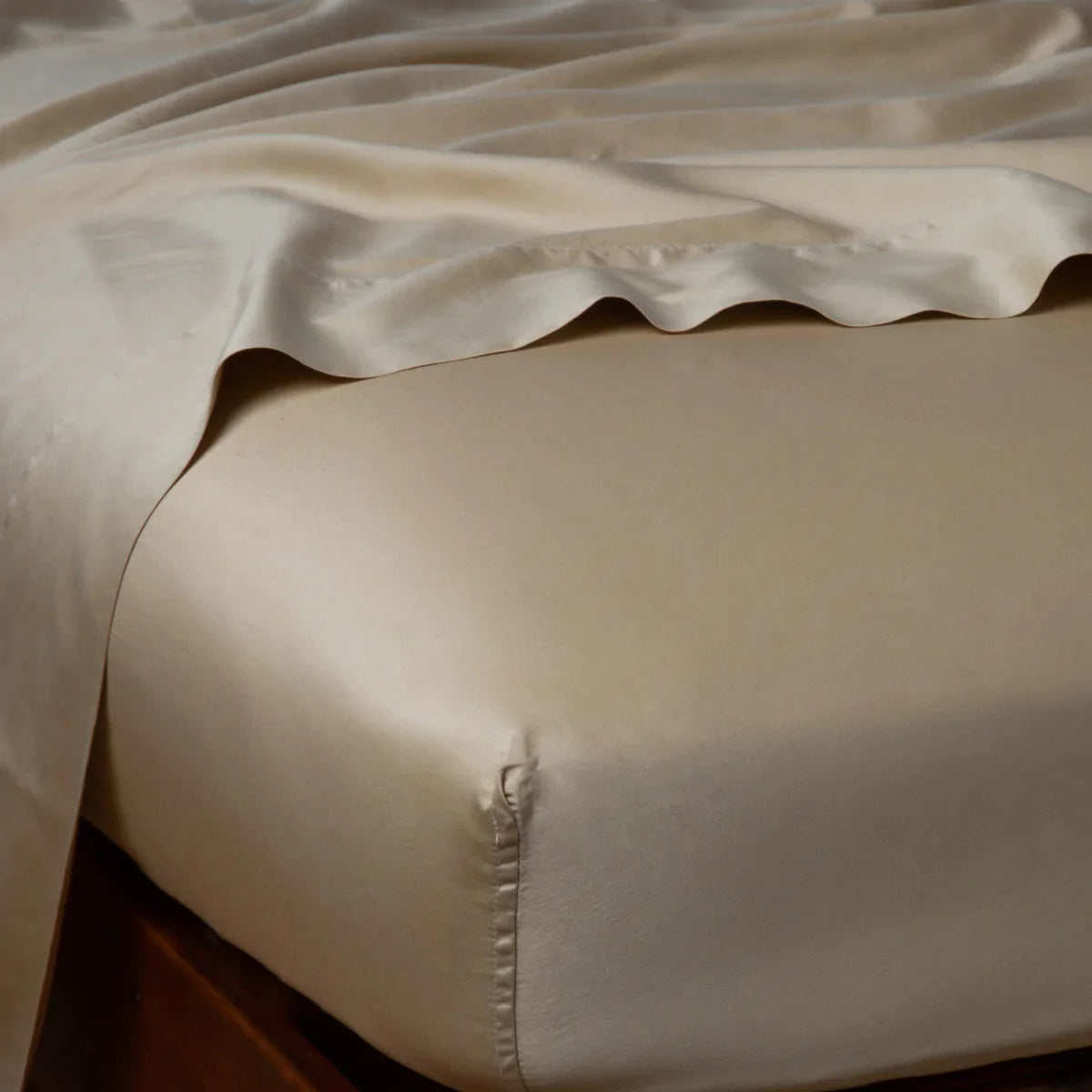 Honeycomb: Cotton sateen flat sheet draped over matching fitted sheet. Shown from the top corner, the flat sheet is rumpled, highlighting the shine of the fabric.
