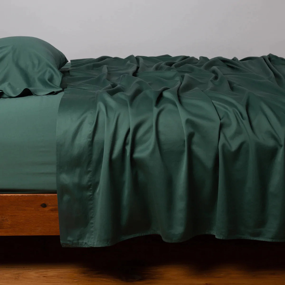 Jade: Cotton sateen flat sheet, shown with matching fitted sheet and sleeping pillow - side view.