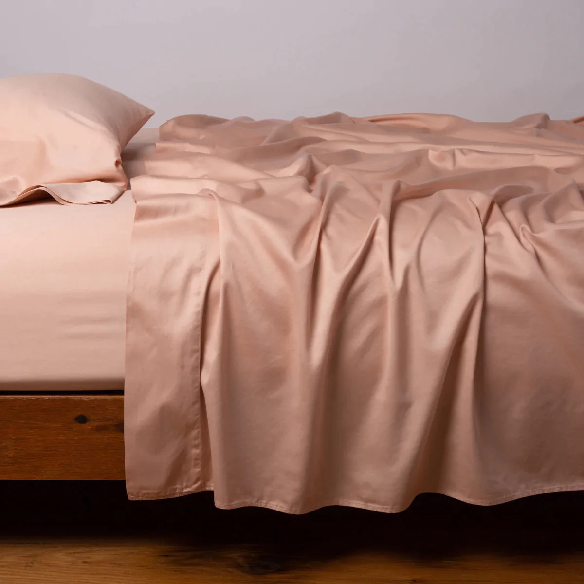 Rouge: Cotton sateen flat sheet, shown with matching fitted sheet and sleeping pillow - side view.