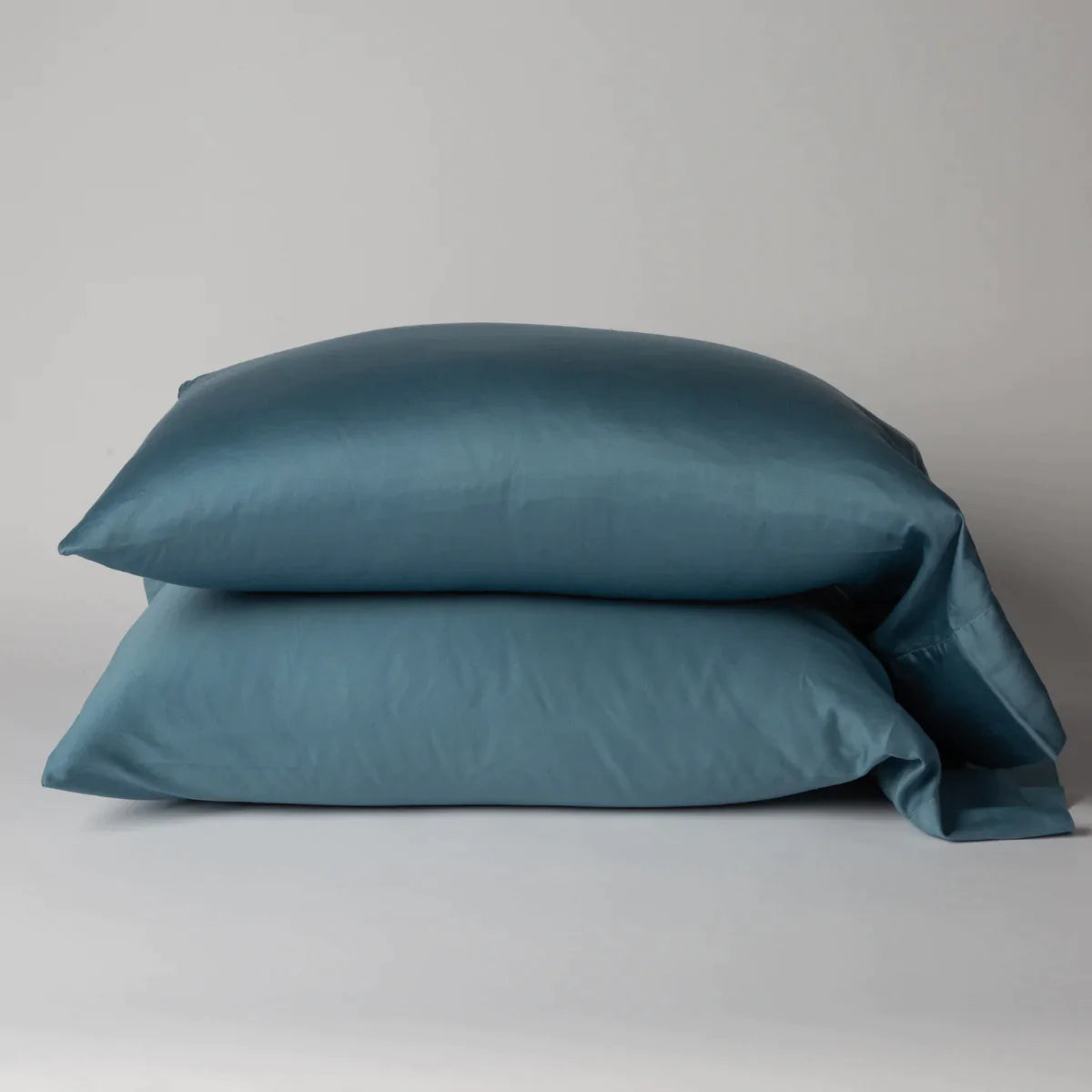 Cenote: Two cotton sateen sleeping pillows, stacked neatly against a white backdrop - side view.