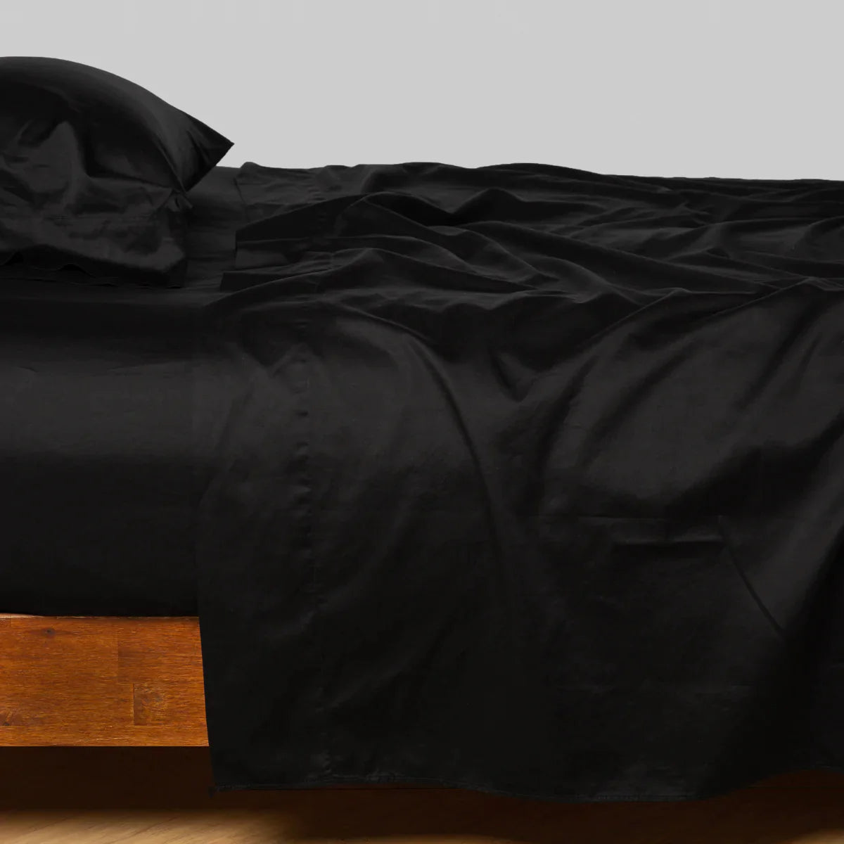 Corvino: Cotton sateen fitted sheet shown with matching flat sheet and sleeping pillow - side view.