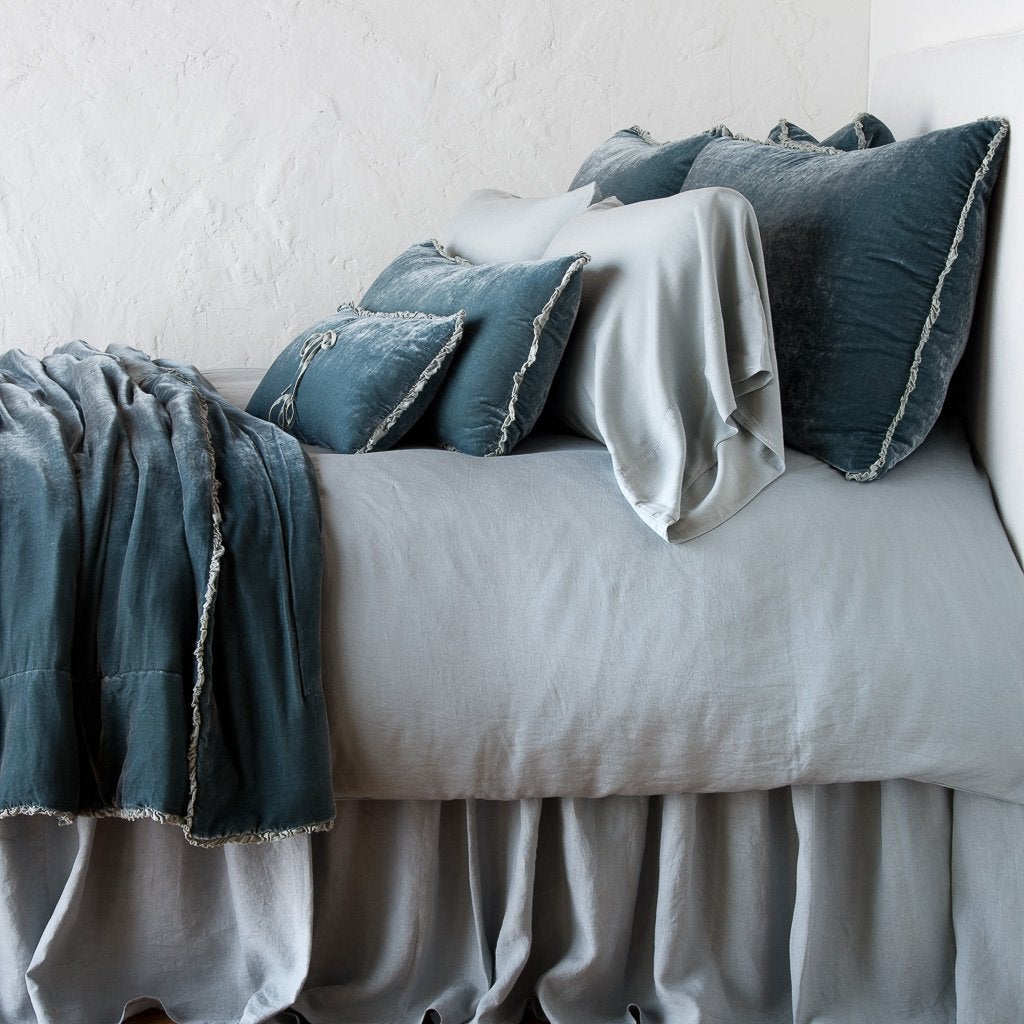 Mineral: Silk velvet throw pillows with petite ruffle on a monochromatic, neatly made bed with matching accessory pieces - side view.