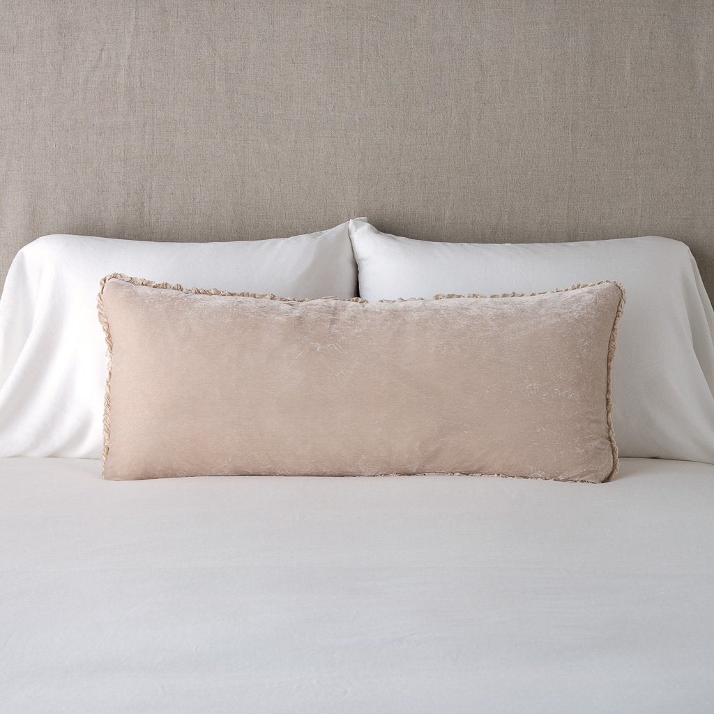 Pearl: Silk velvet lumbar pillow with petite ruffle, leaning upright against neutral bedding and headboard.