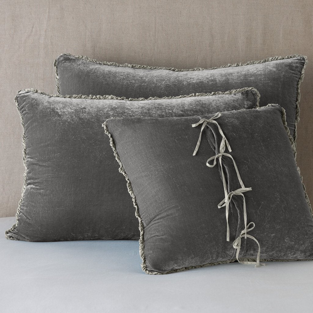 Fog: Silk velvet shams with a petite ruffle leaning upright against a neutral headboard. The front sham is backwards, showcasing the charmeuse tie closures.