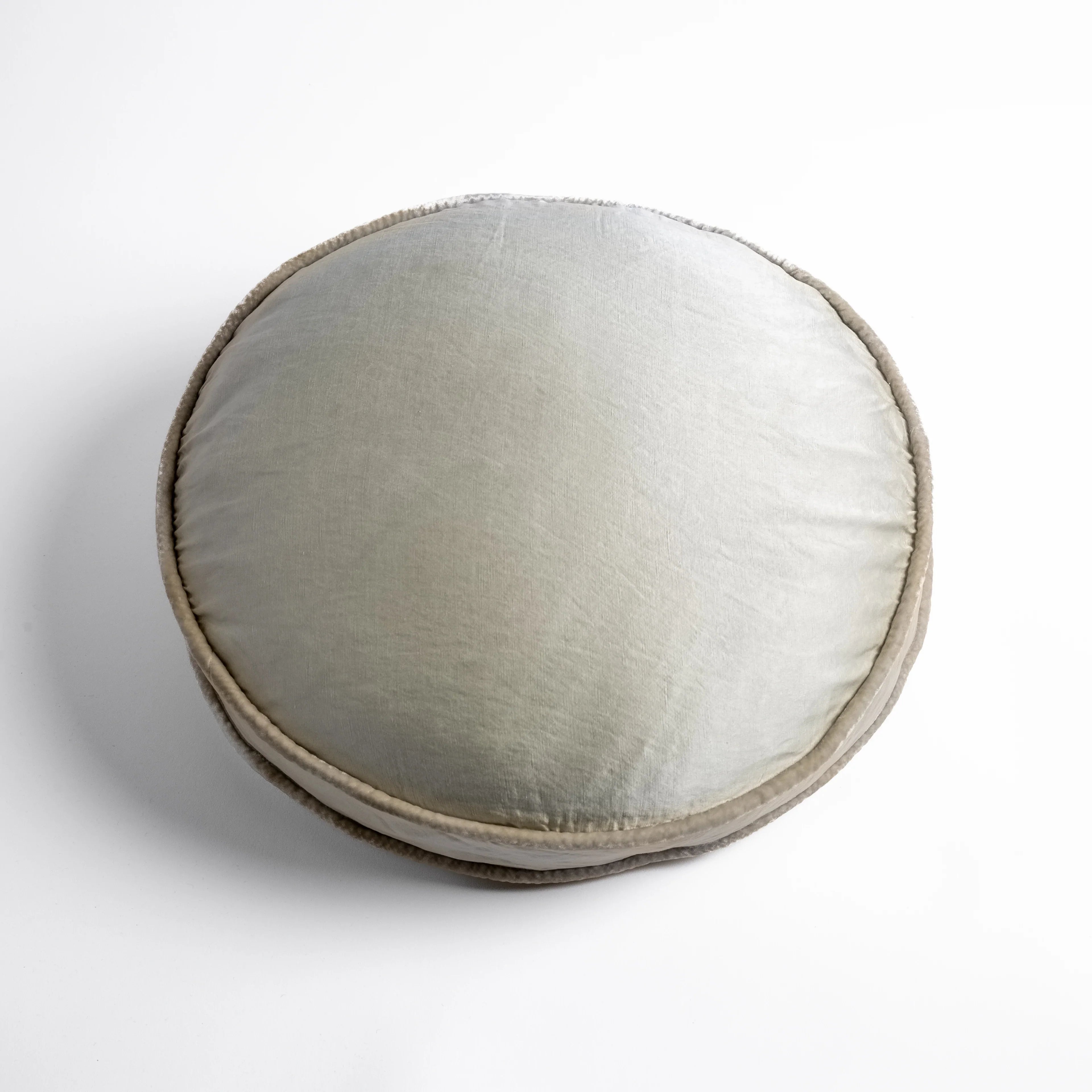 Parchment: 18" round charmeuse pillow with silk velvet trim at gusset shot from overhead on a white background
