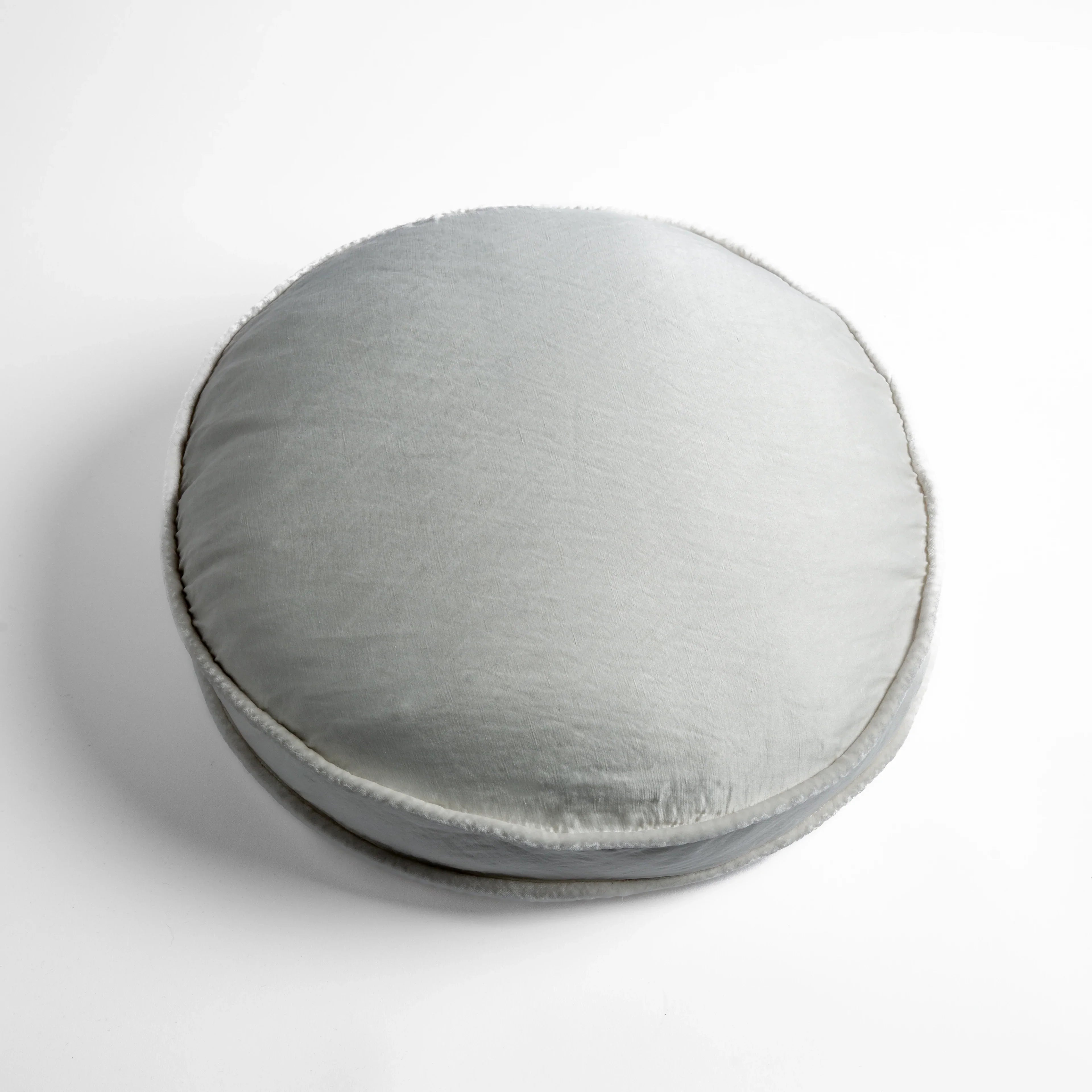 Winter White: 18" round charmeuse pillow with silk velvet trim at gusset shot from overhead on a white background