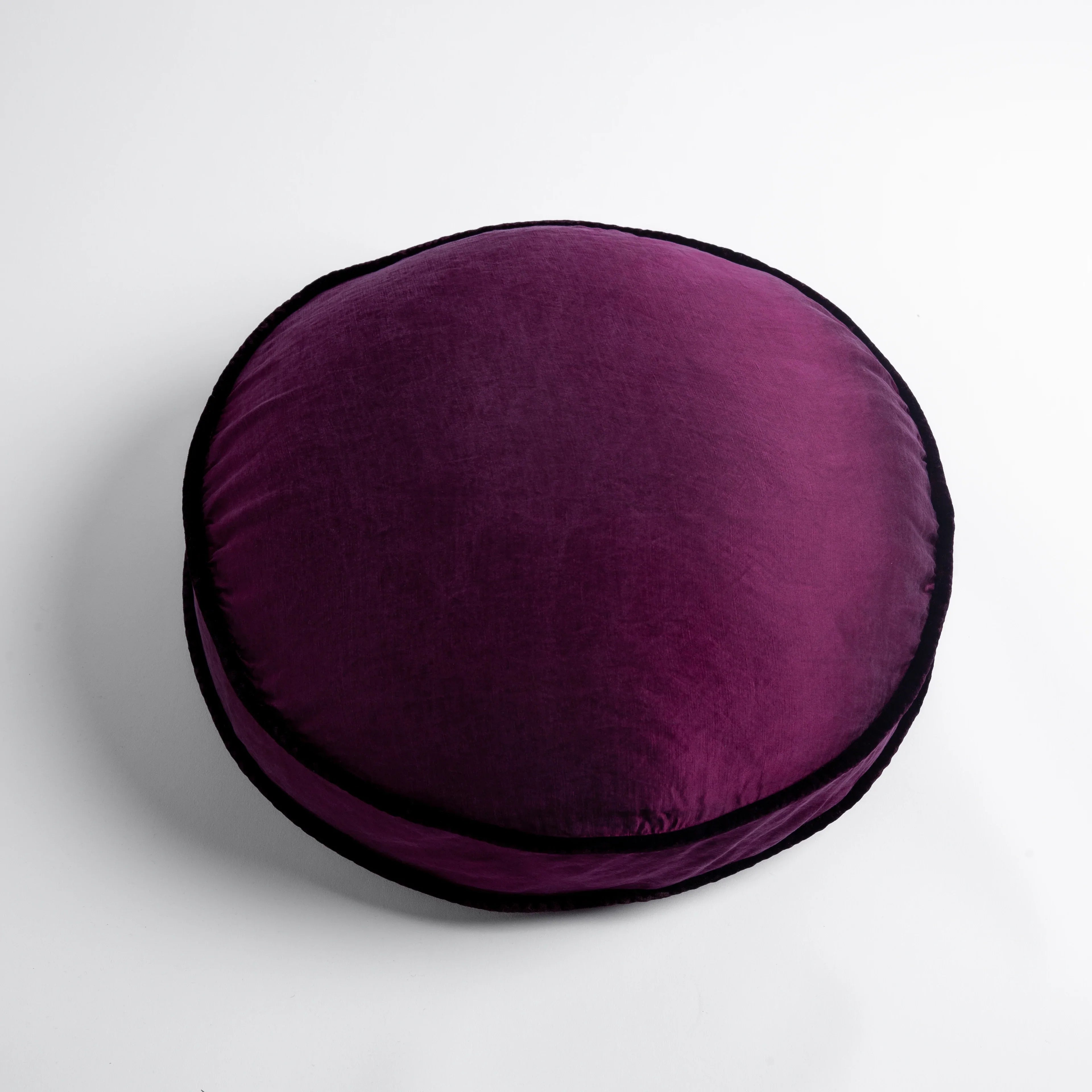 Fig: 18" round charmeuse pillow with silk velvet trim at gusset shot from overhead on a white background