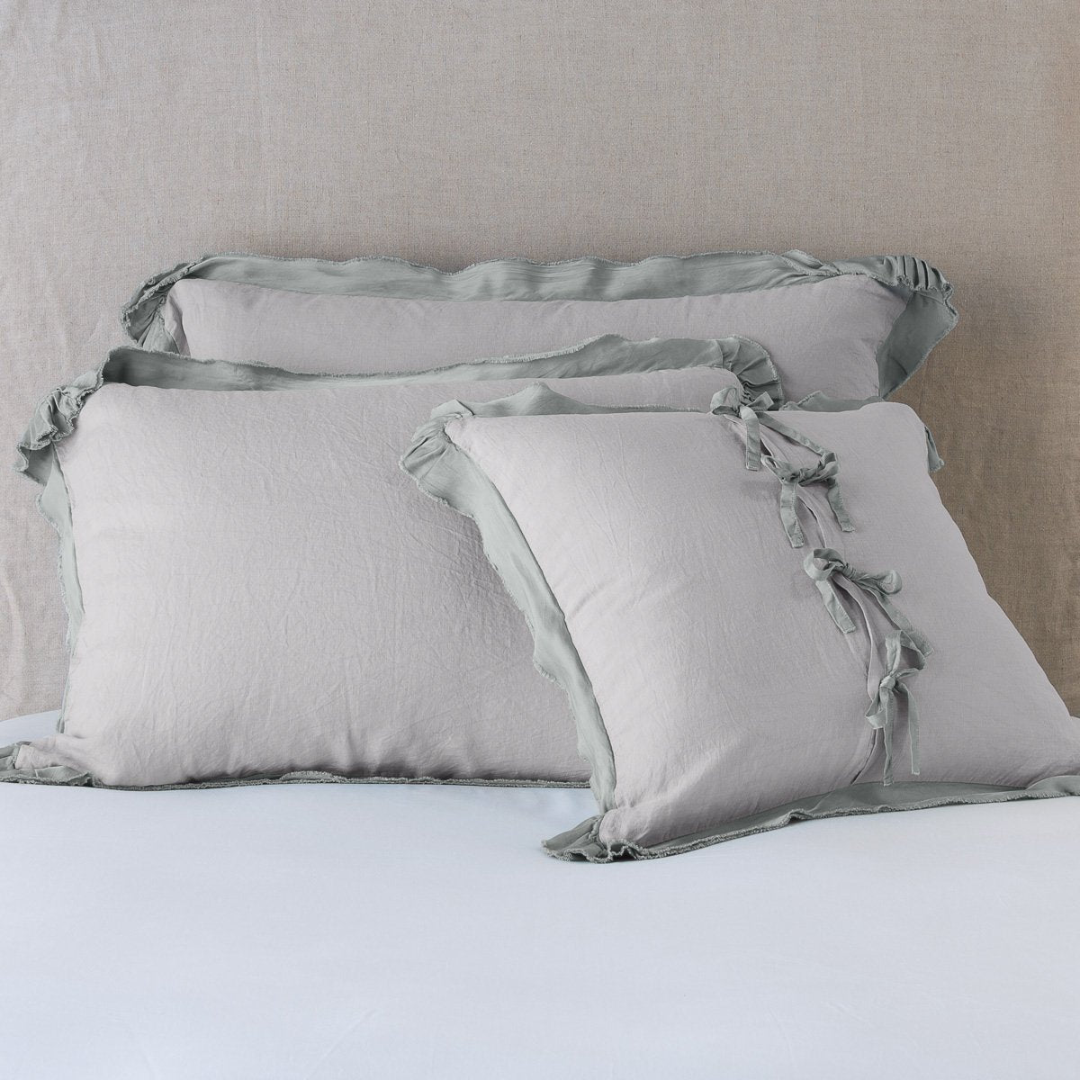 Fog: satin trimmed linen shams showing the front and back of the sham with tie closures.