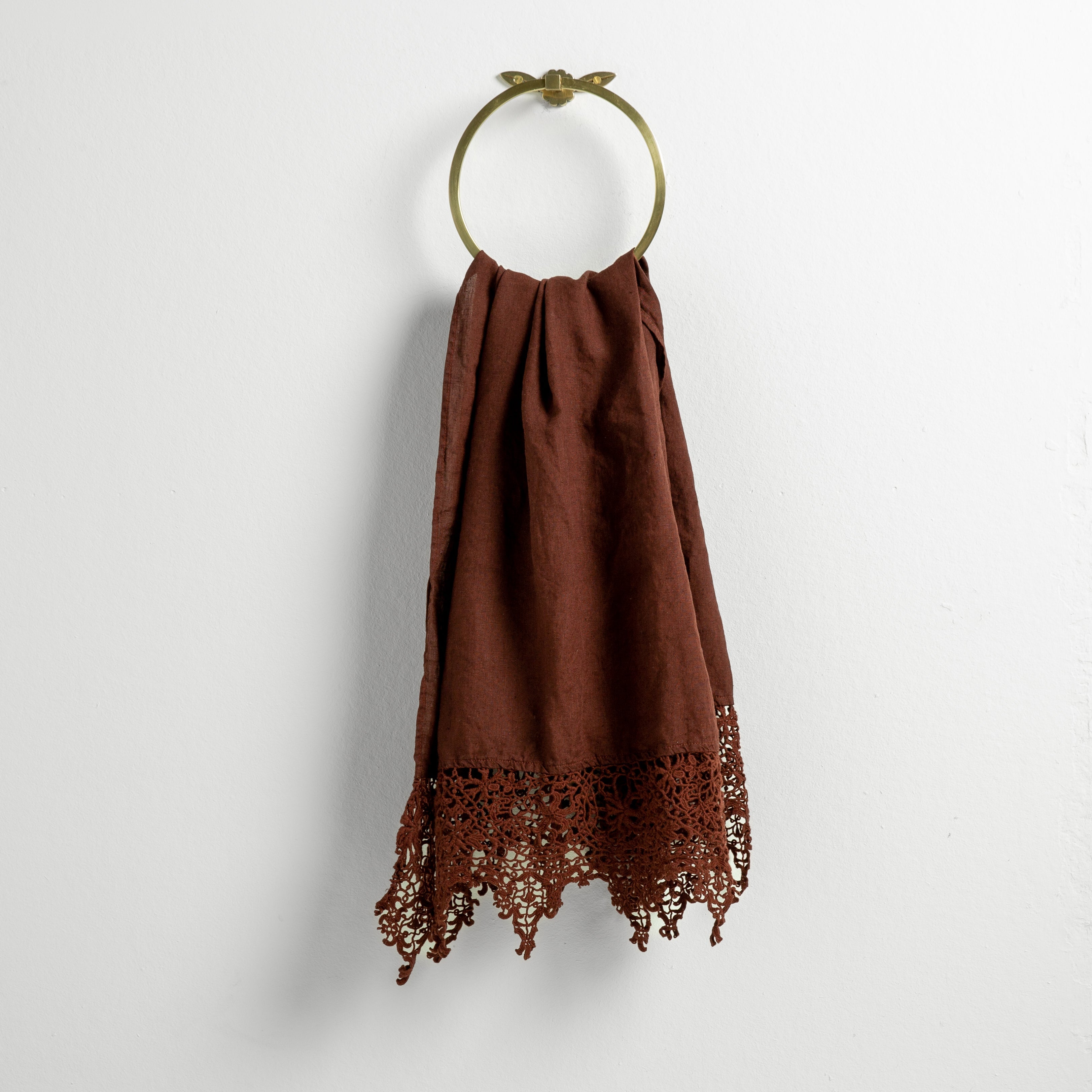 Mahogany: Lace trimmed linen guest towel draped through a decorative towel ring against a plain white background.