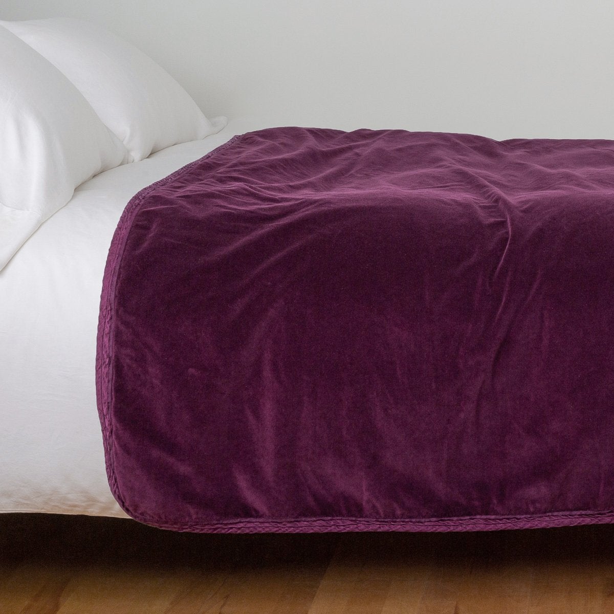 Fig: Cotton velvet bed end sized blanket, draped on a white bed - side view.