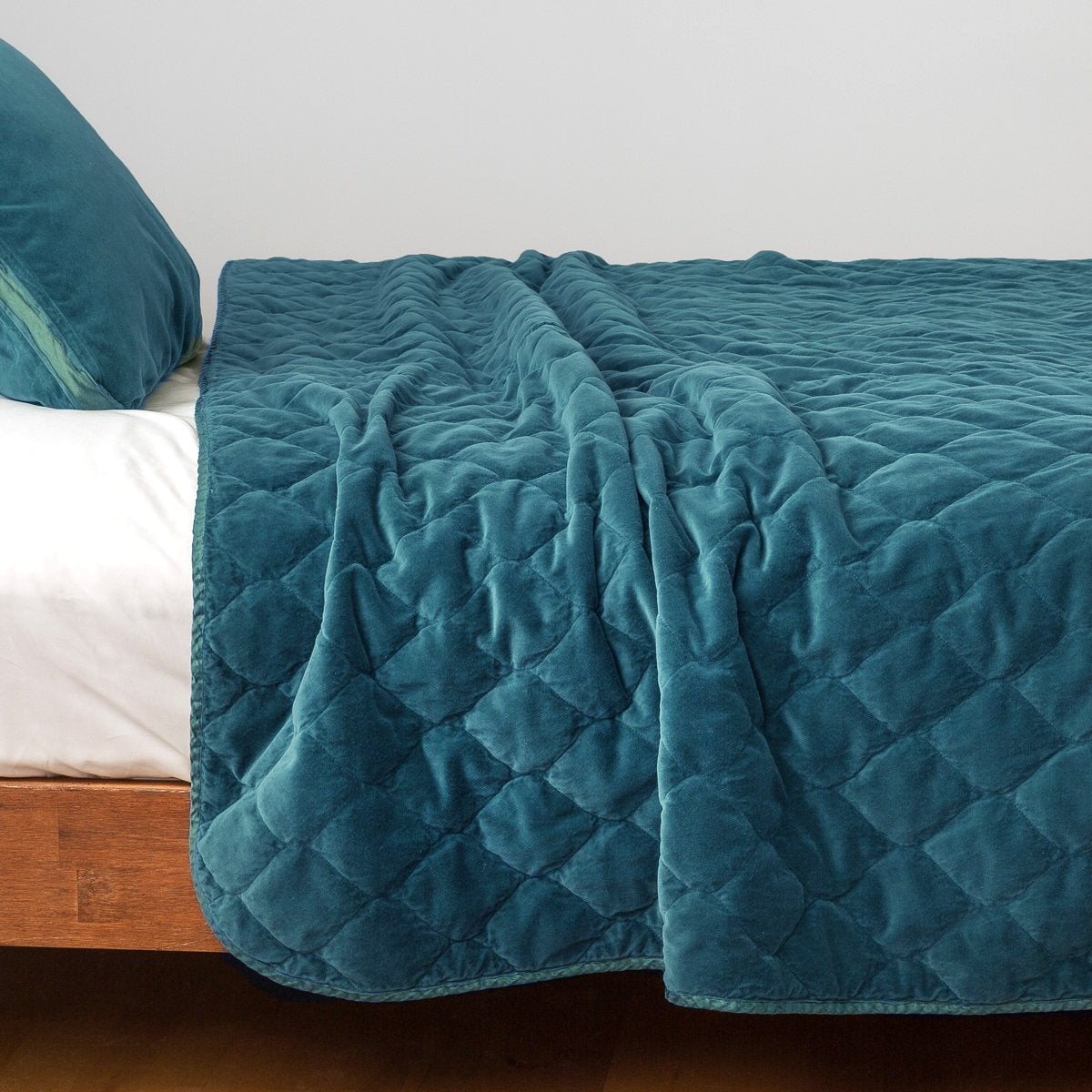 : Harlow coverlet in cenote, draped over a white fitted sheet - side view.