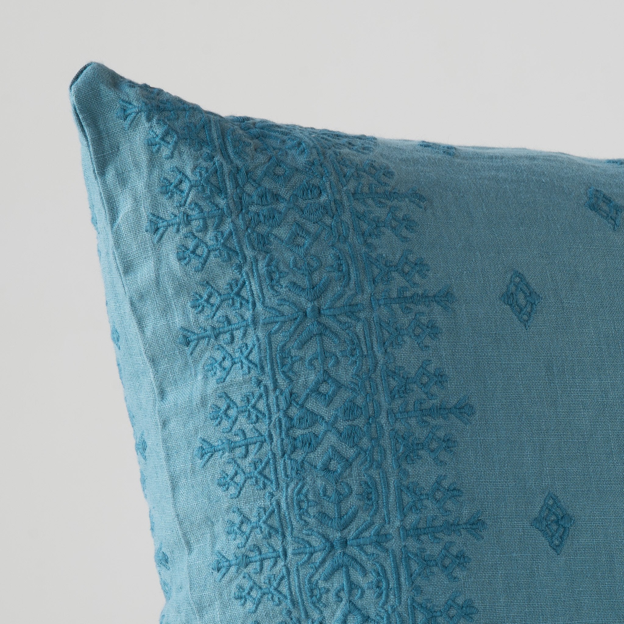 Cenote: Close-up of pillow corner, showcasing the embroidery pattern detail.