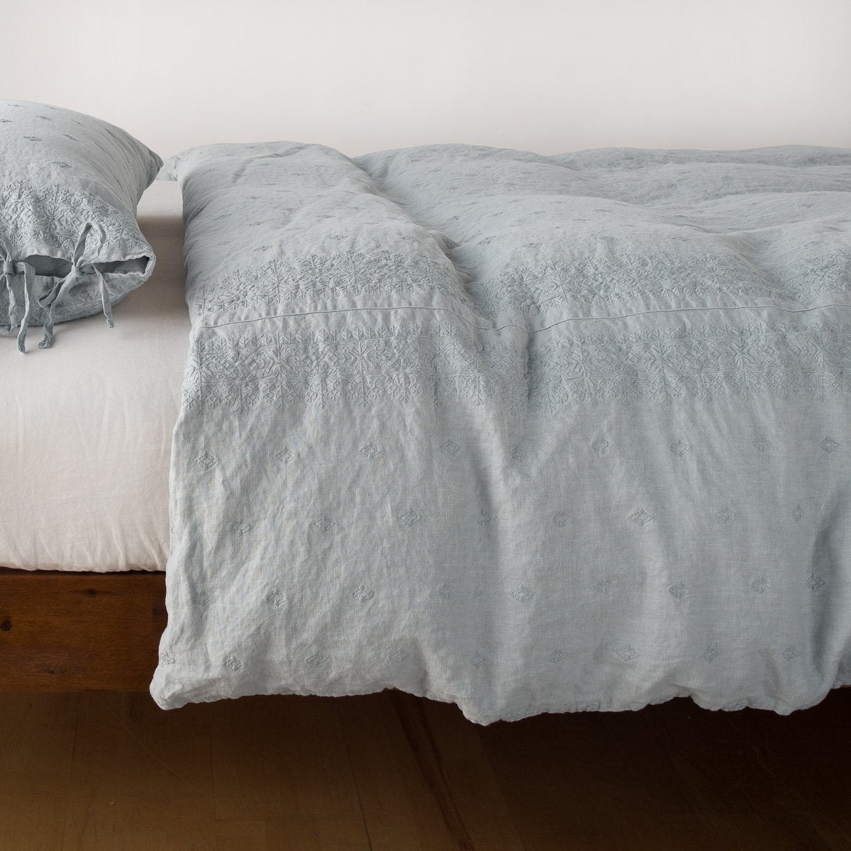 Mineral: lightly rumpled duvet cover on a monochromatic bed against a white background - side view.