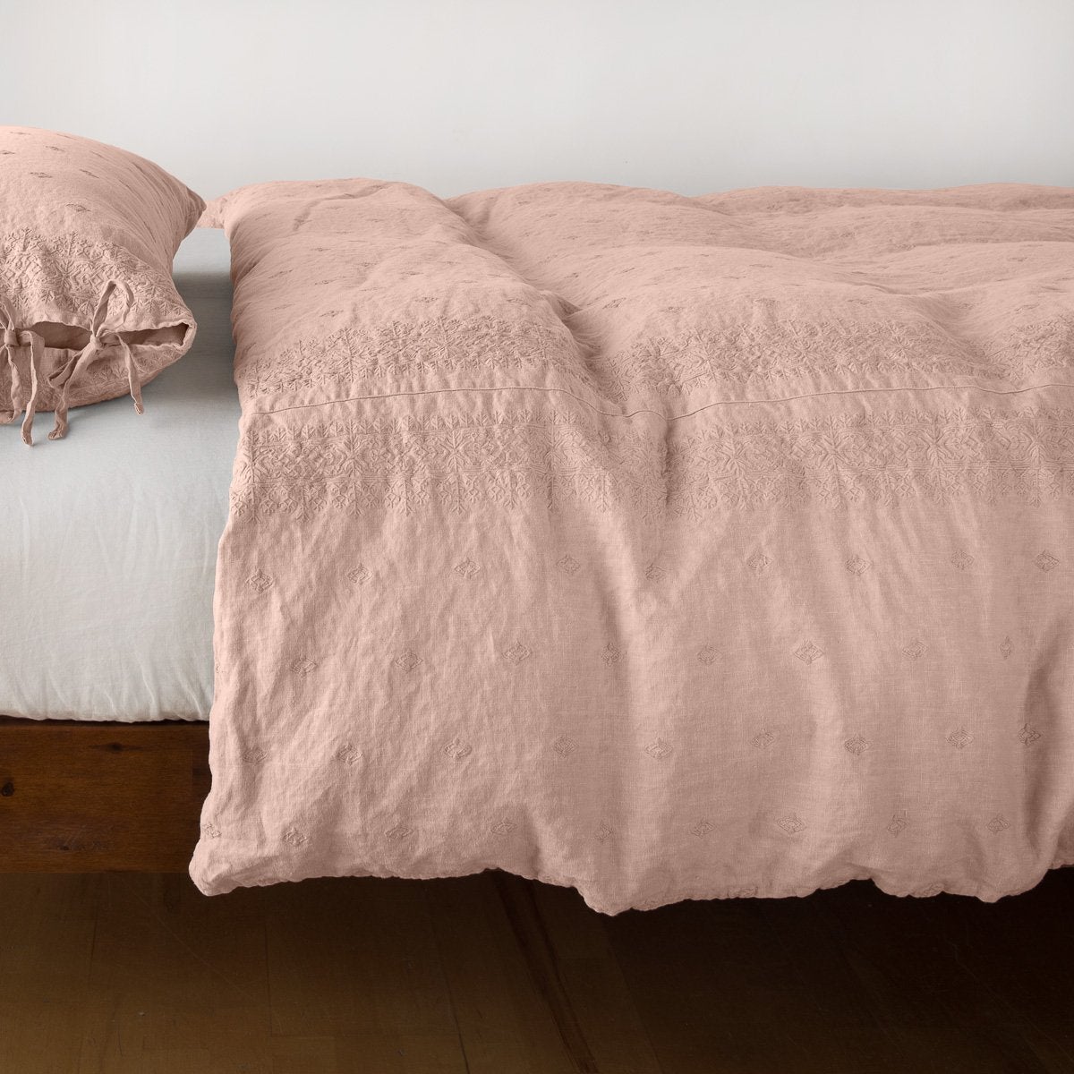 Rouge: lightly rumpled duvet cover on a monochromatic bed against a white background - side view.