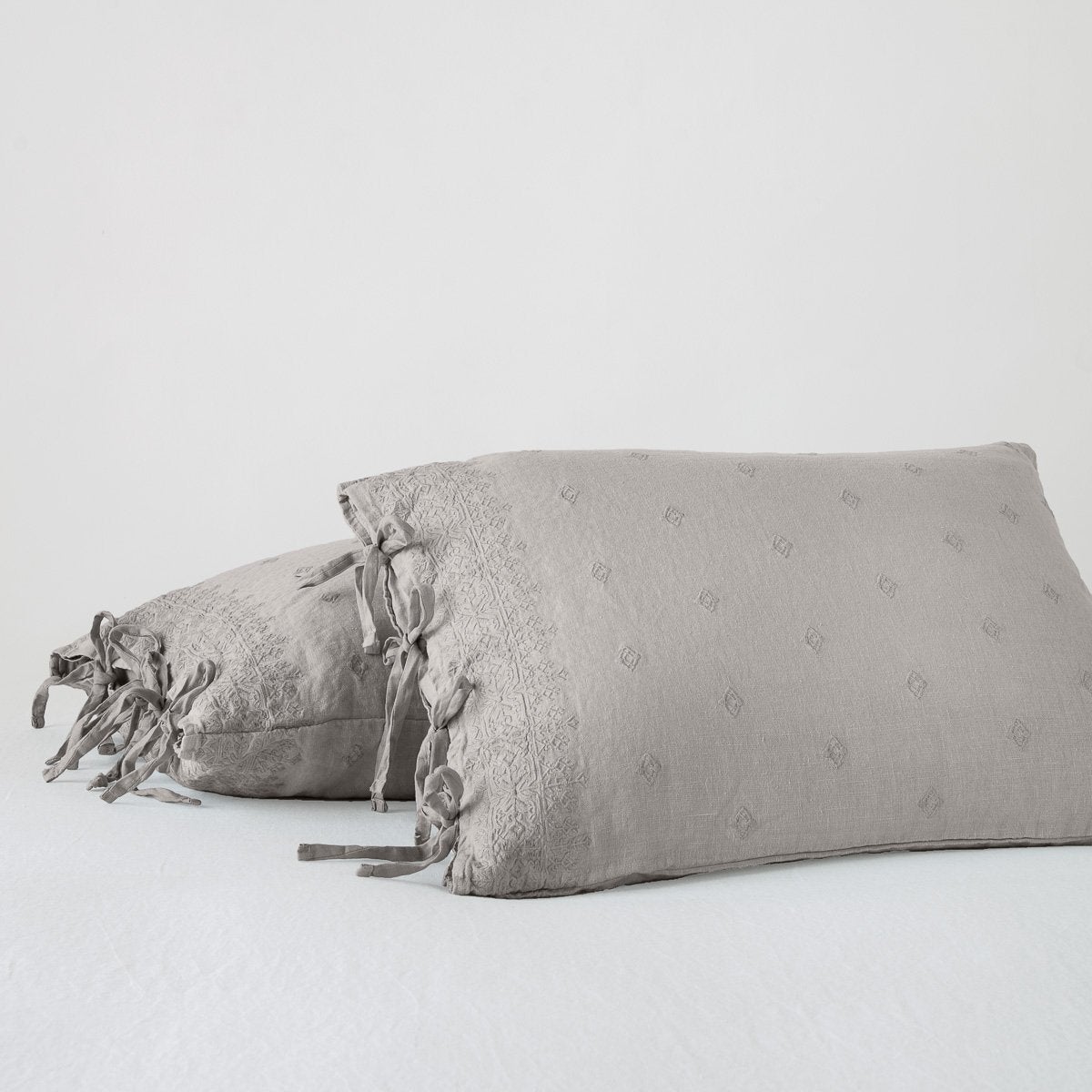 Fog: standard sham leaning against a king sham, on a white background and at a slight angle to showcase the linen side-tie closure.