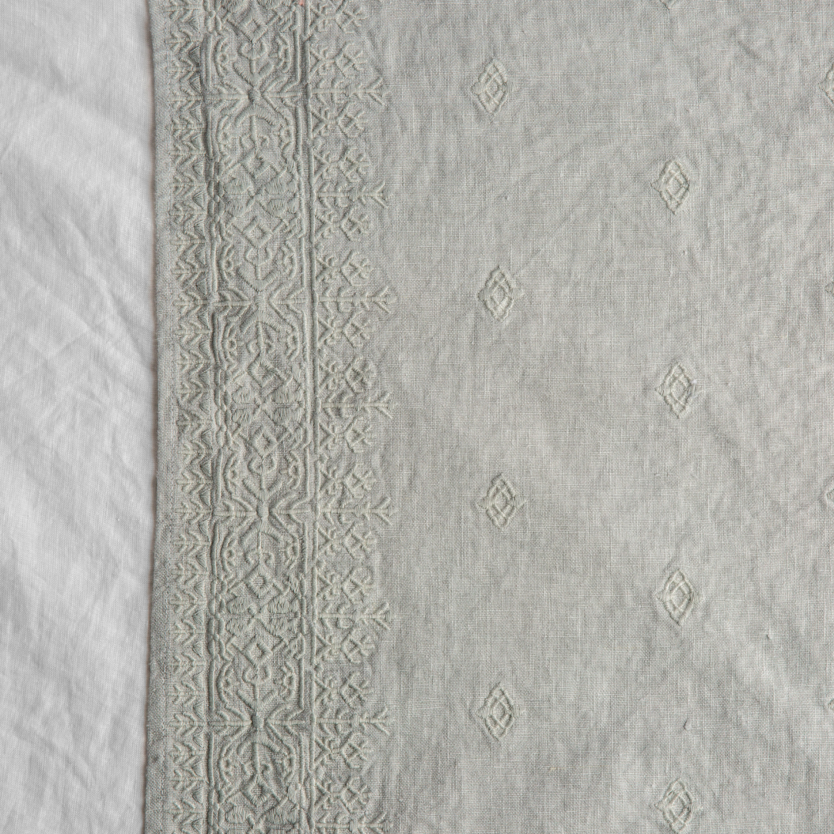 Eucalyptus: A close up of Ines, midweight linen with cotton embroidery, in cloud, a soft, subtle sky blue-grey.