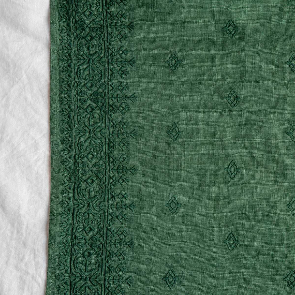 Jade: A close up of Ines, midweight linen with cotton embroidery, in jade, a rich, verdant green with subtle blue undertones.