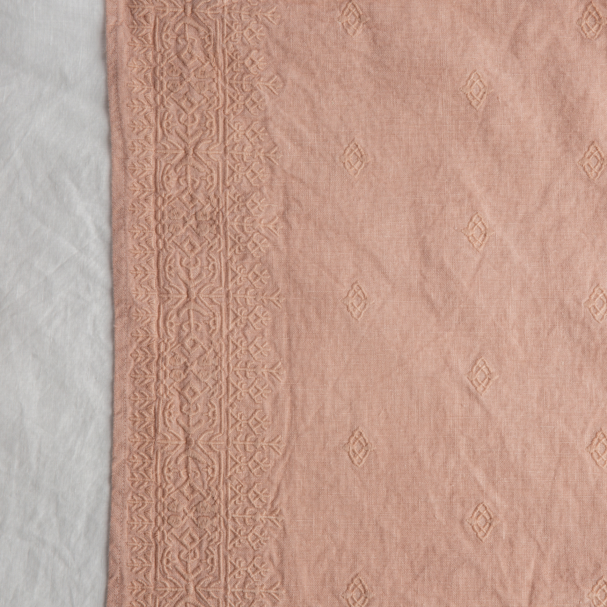 Rouge: A close up of Ines, midweight linen with cotton embroidery, in white.