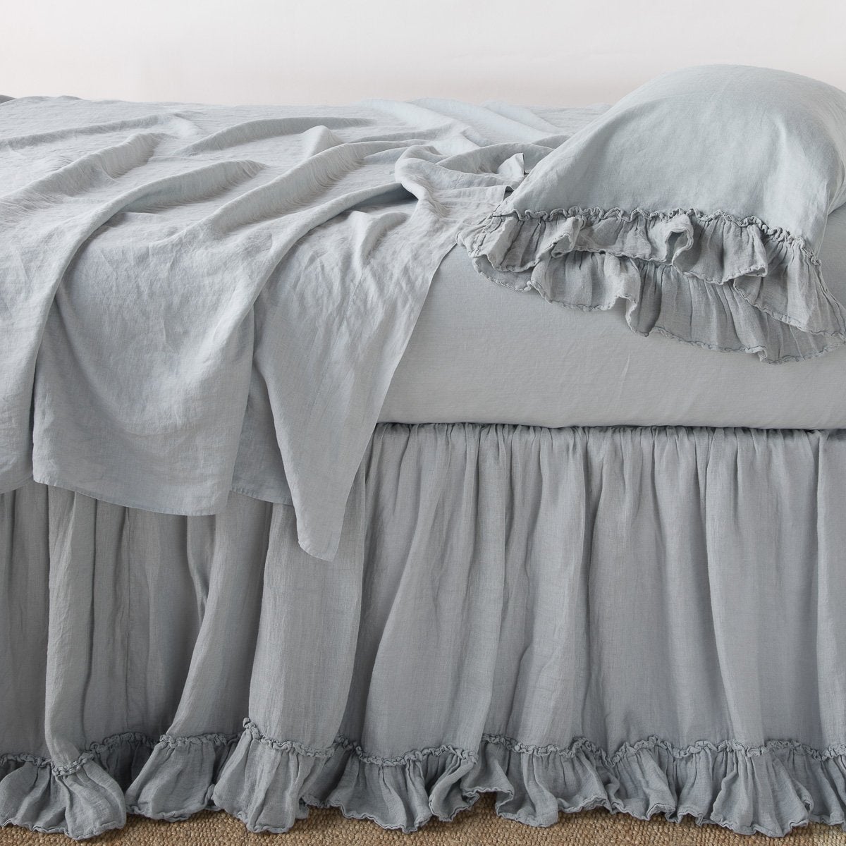 : Linen whisper bed skirt on a bed with monochromatic linen sheeting - mineral, side view.