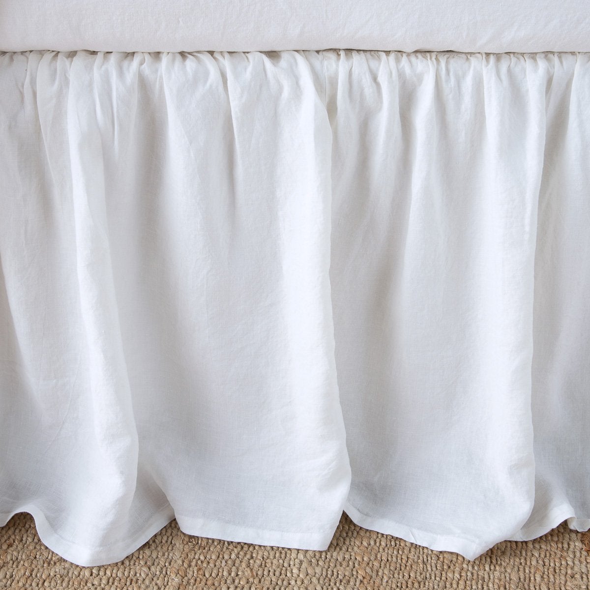 : Close-up of linen bed skirt in white, featuring its softly gathered design.
