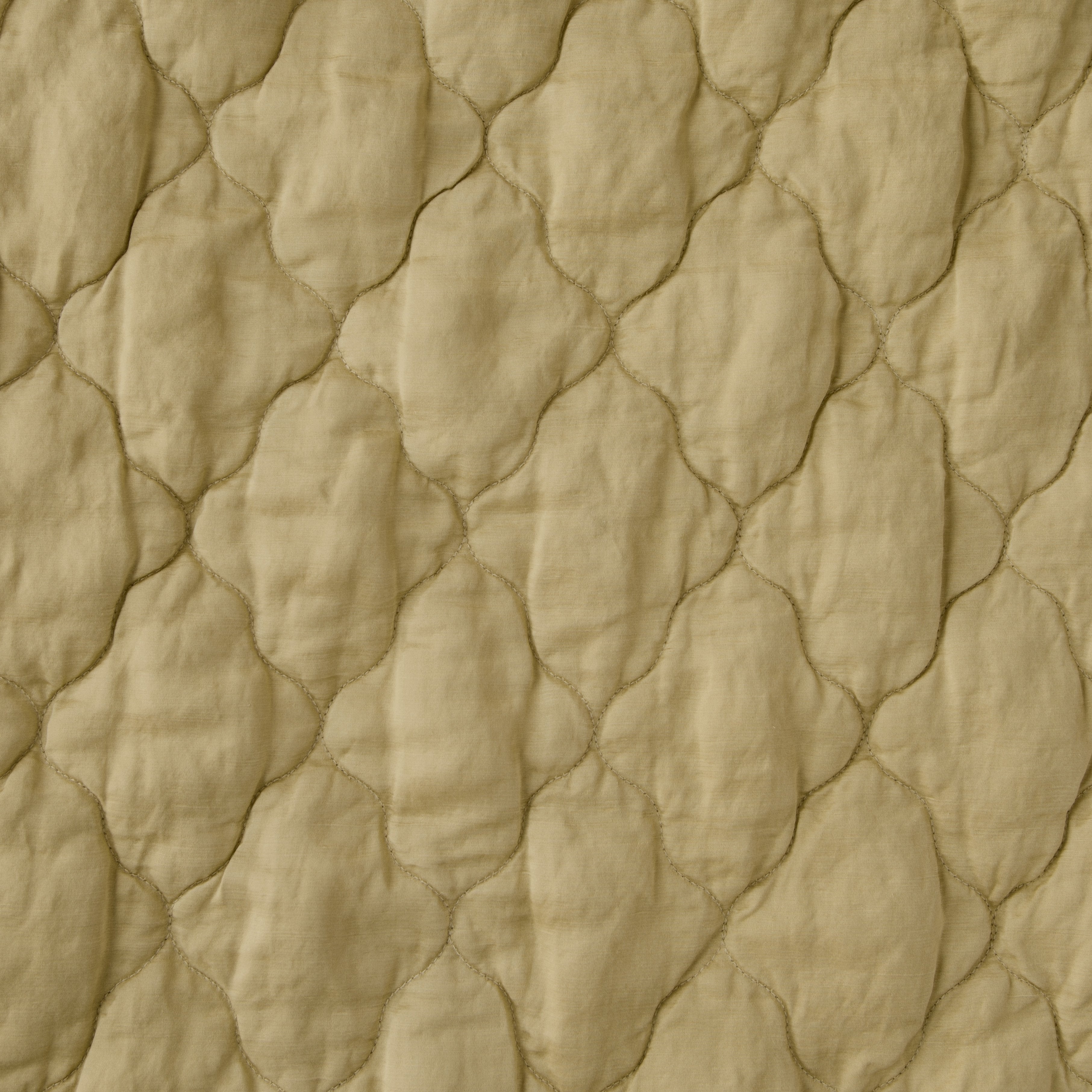 Honeycomb: Close-up of Luna silk charmeuse quilting in honeycomb, a warm golden tone.