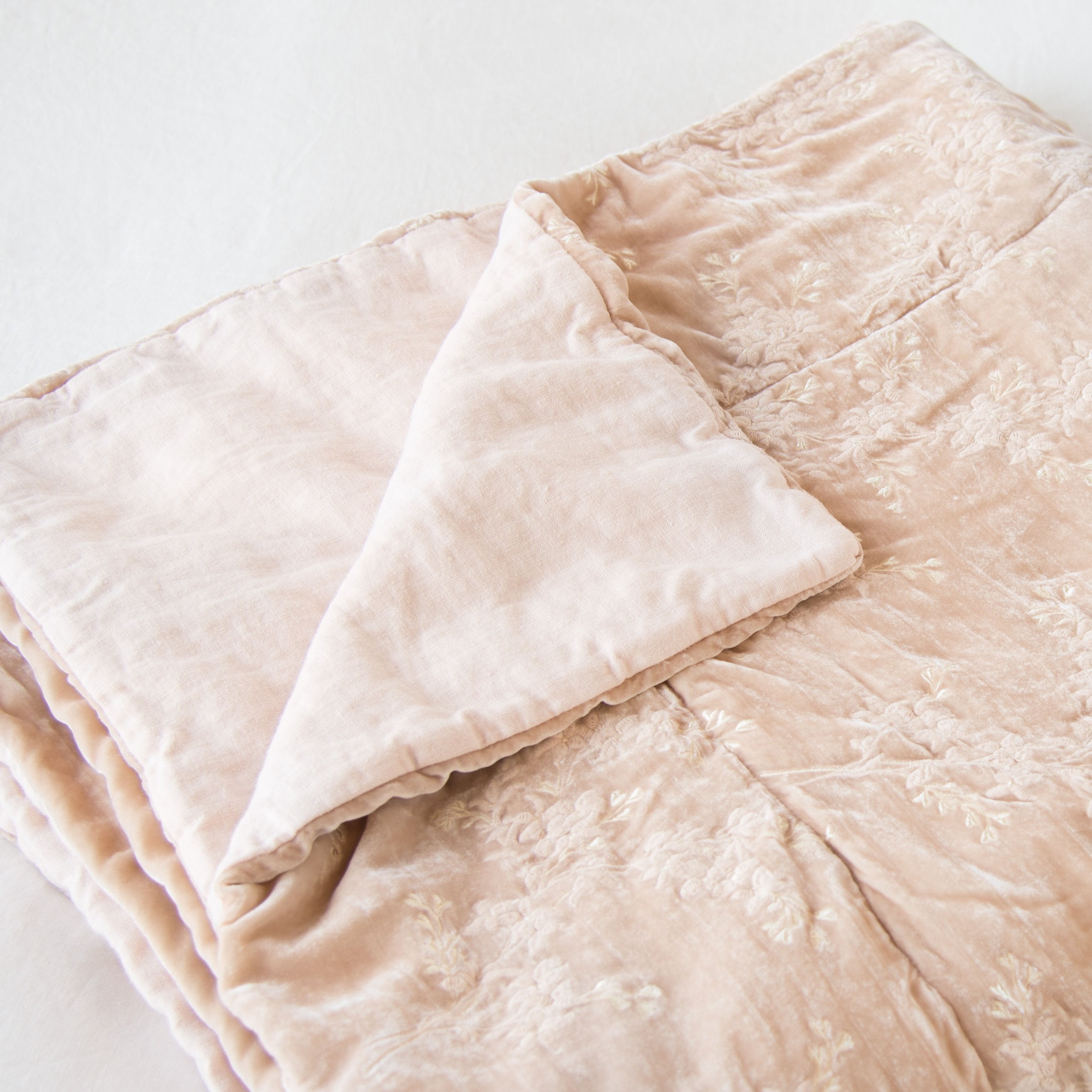 Pearl: Lynette throw blanket in pearl, neatly folded on a light background, with a corner turned back to showcase the linen back - slight overhead angle.