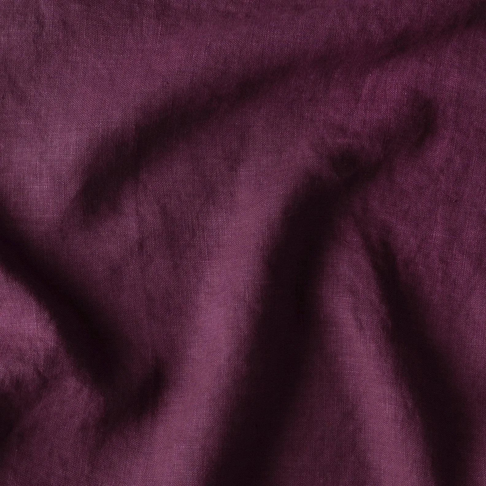 Fig: A close up of midweight linen in fig, a richly saturated purple-garnet.