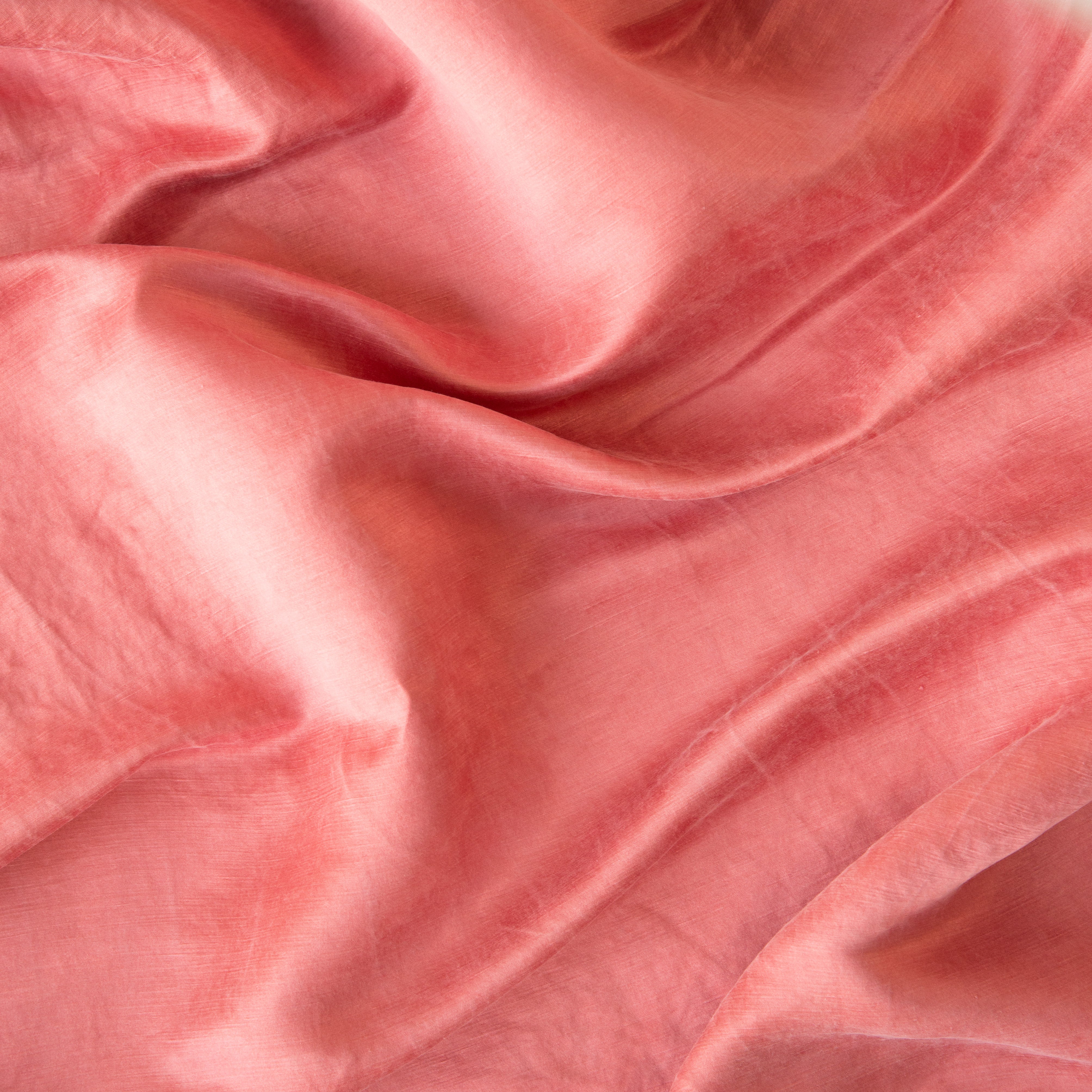 Poppy: Close-up of silk charmeuse in poppy, a warm coral pink.