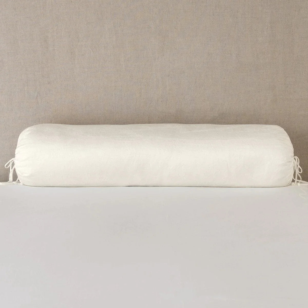 Parchment: bolster on white sheets with a neutral headboard.