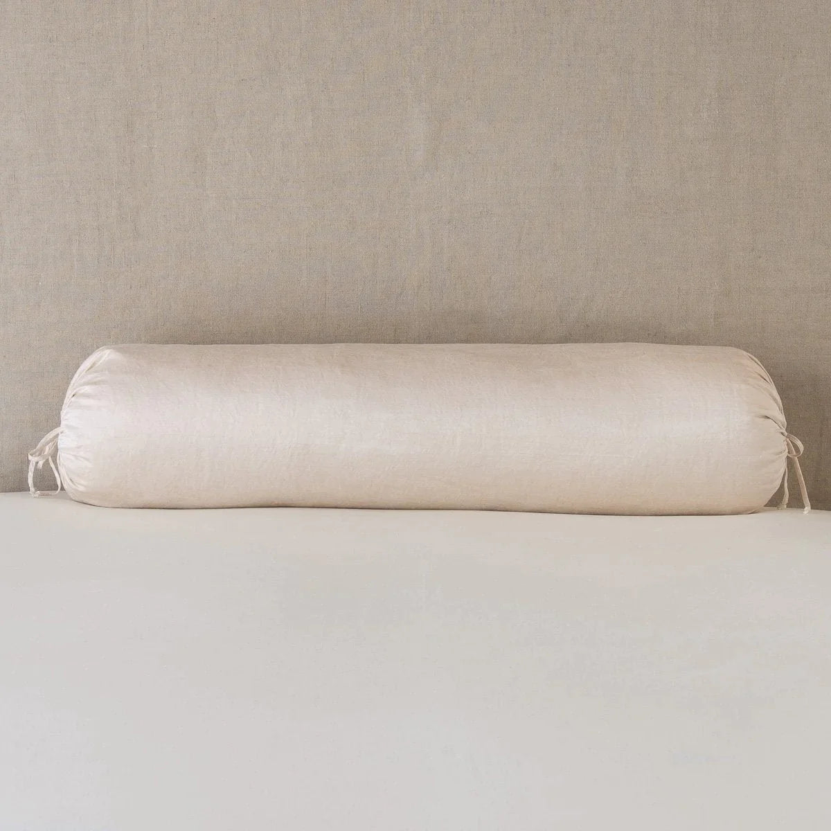 Pearl: bolster on white sheets with a neutral headboard.