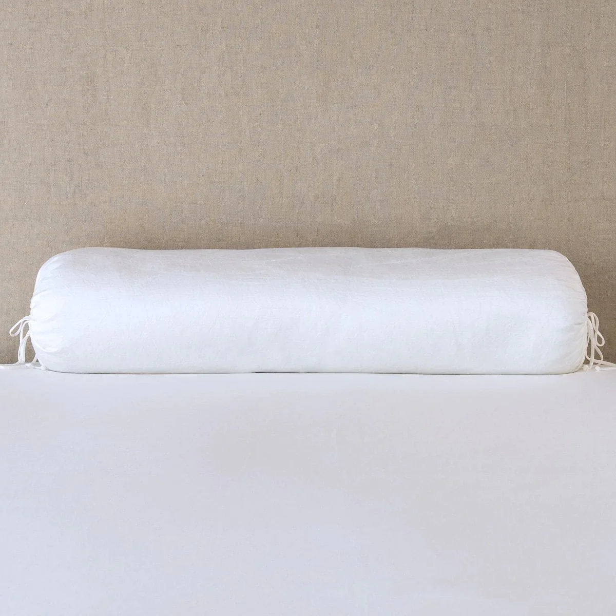 White: bolster on white sheets with a neutral headboard.