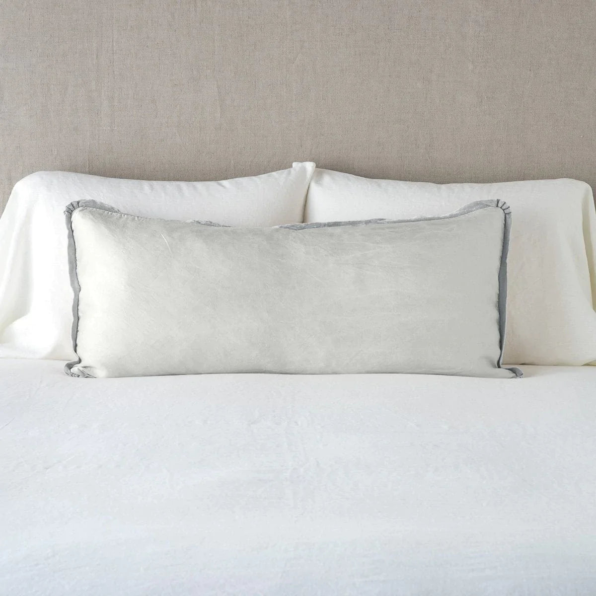 Sterling: 16x36 charmeuse pllow wth silk velvet trim against white sleeping pillows and sheets — straight on with neutral background.