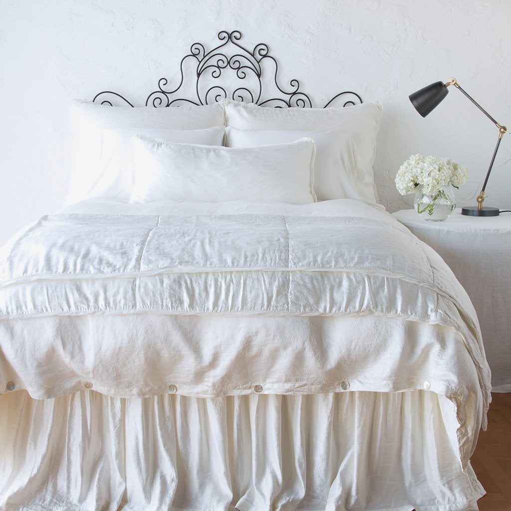 Winter White: throw blanket folded at the end of a monochromatic, charmeuse bed - end of bed view.