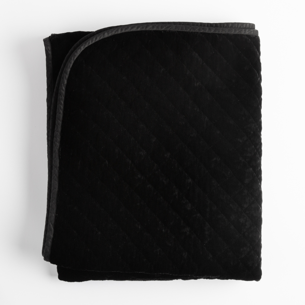 Corvino: quiilted silk vevlet trimmed with satin in a dark black tone shot overhead on a white background.