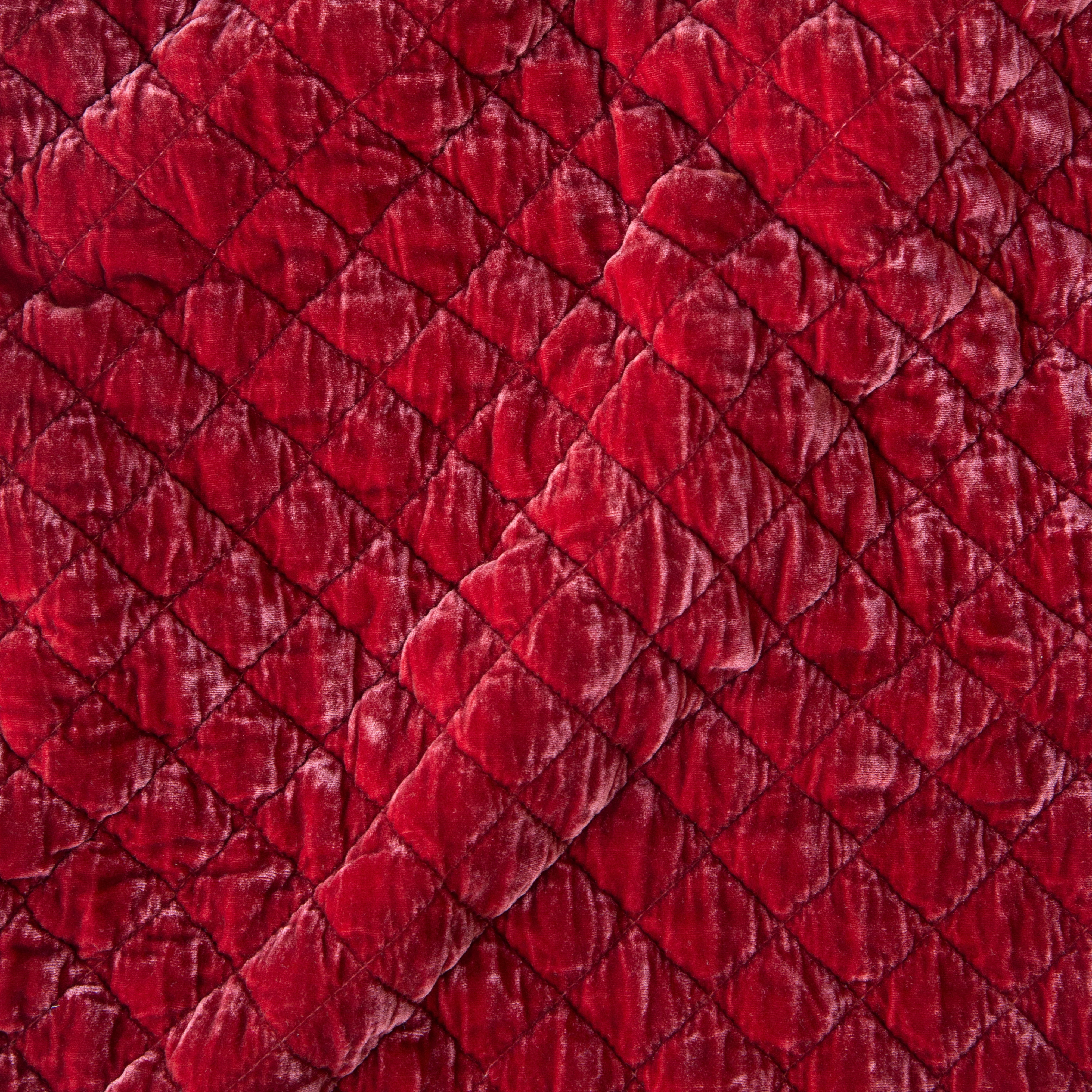Poppy: Close-up of quilted silk velvet in poppy, a vibrant reddish pink.