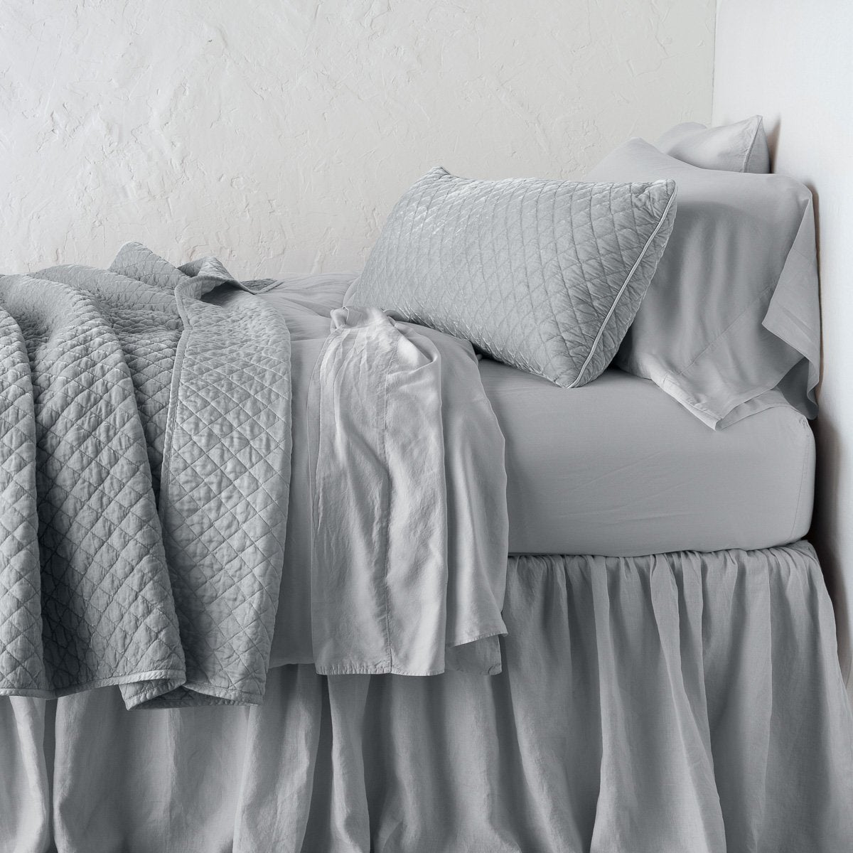 Sterling: 16x36 pillow with rumpled matching coverlet on monochromatic bed - side view.