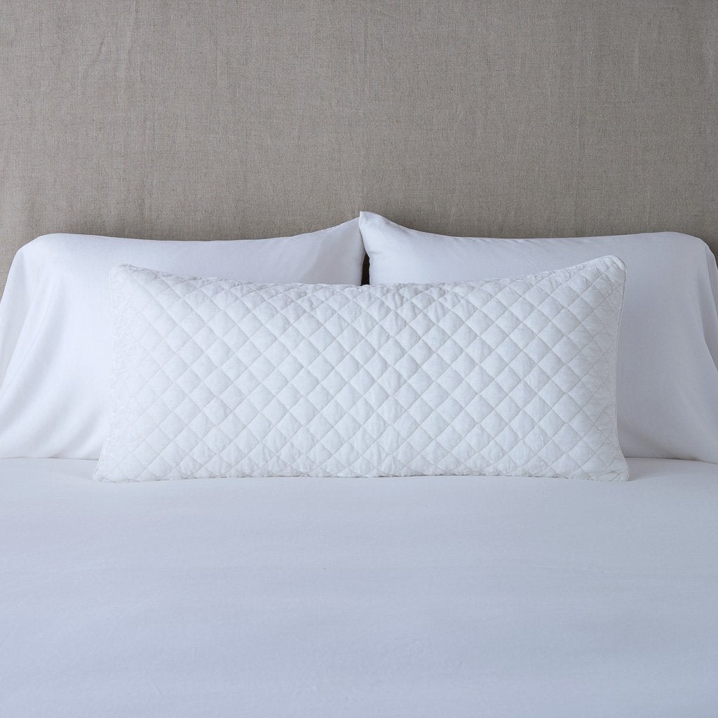 White: 16x36 pillow leaning upright against white sleeping pillows and a neutral headboard.
