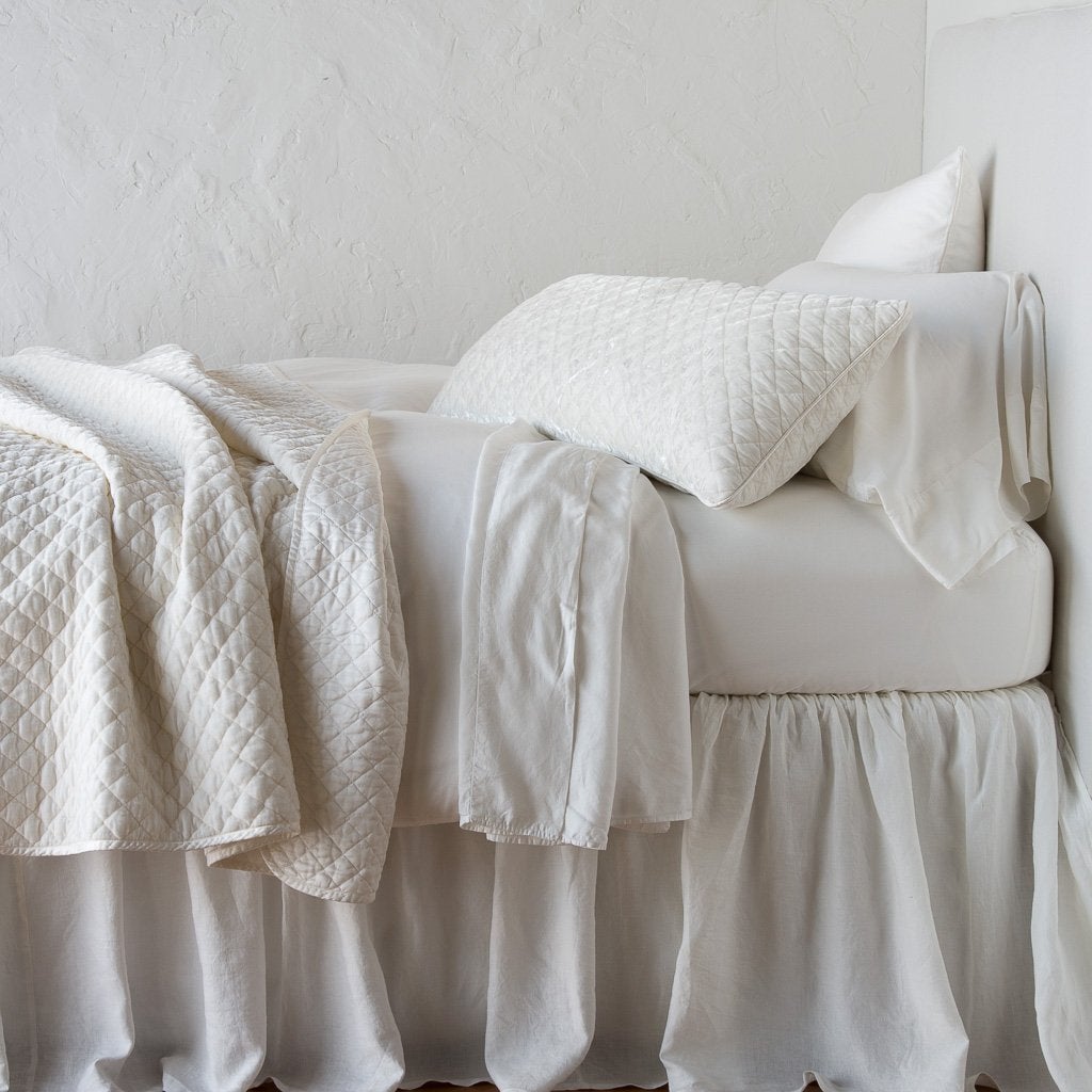 Winter White: 16x36 pillow with rumpled matching coverlet on monochromatic bed - side view.