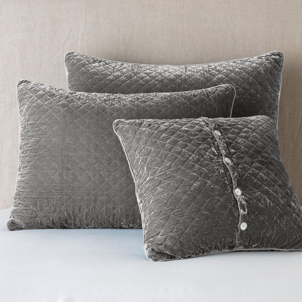Fog: shams leaning upright against a neutral headboard. One sham is backwards to showcase the shimmering shell button closure.