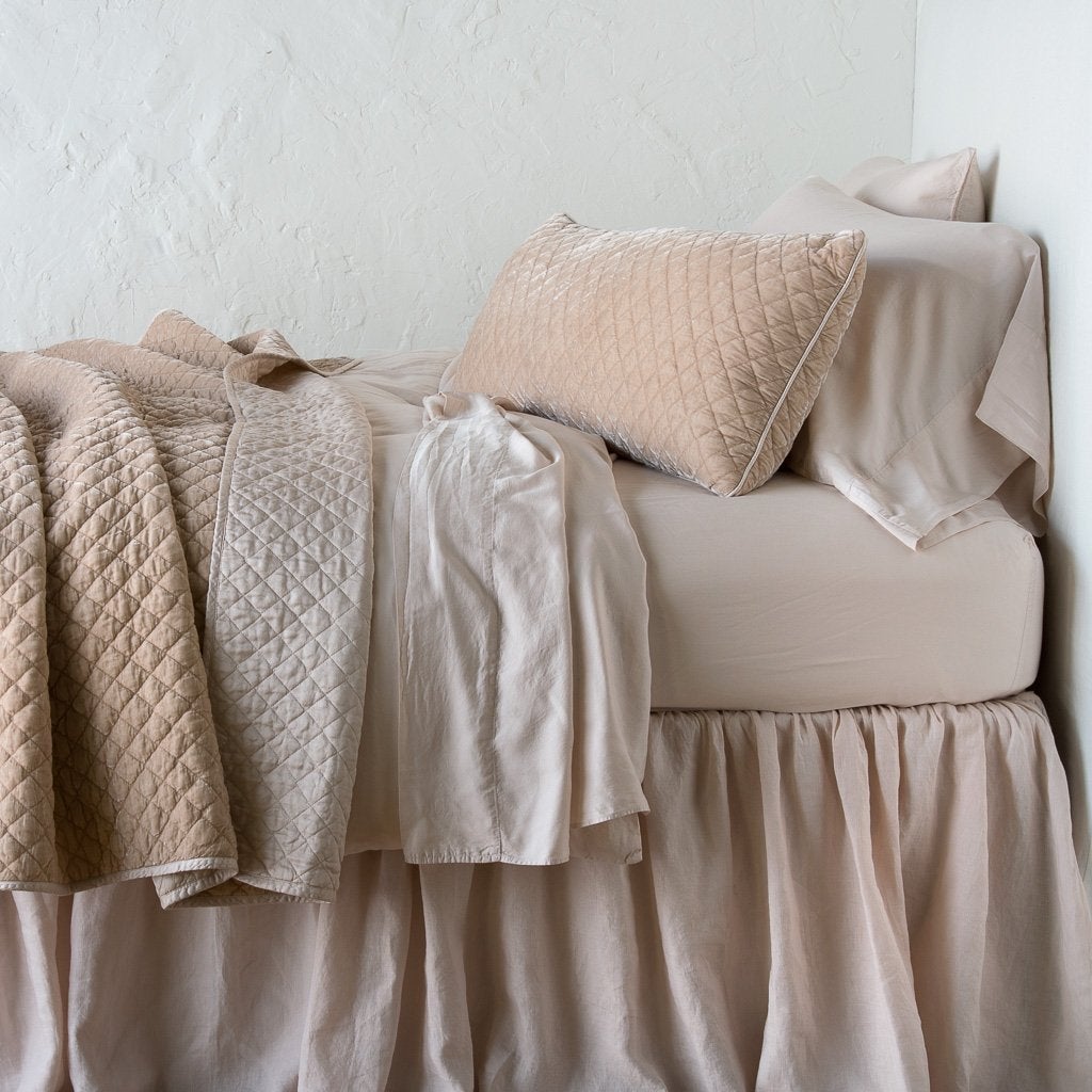 : Silk velvet throw blanket rumpled and folded back, featuring satin back. Shown with matching lumbar pillow and monochromatic sheeting - pearl, side view.