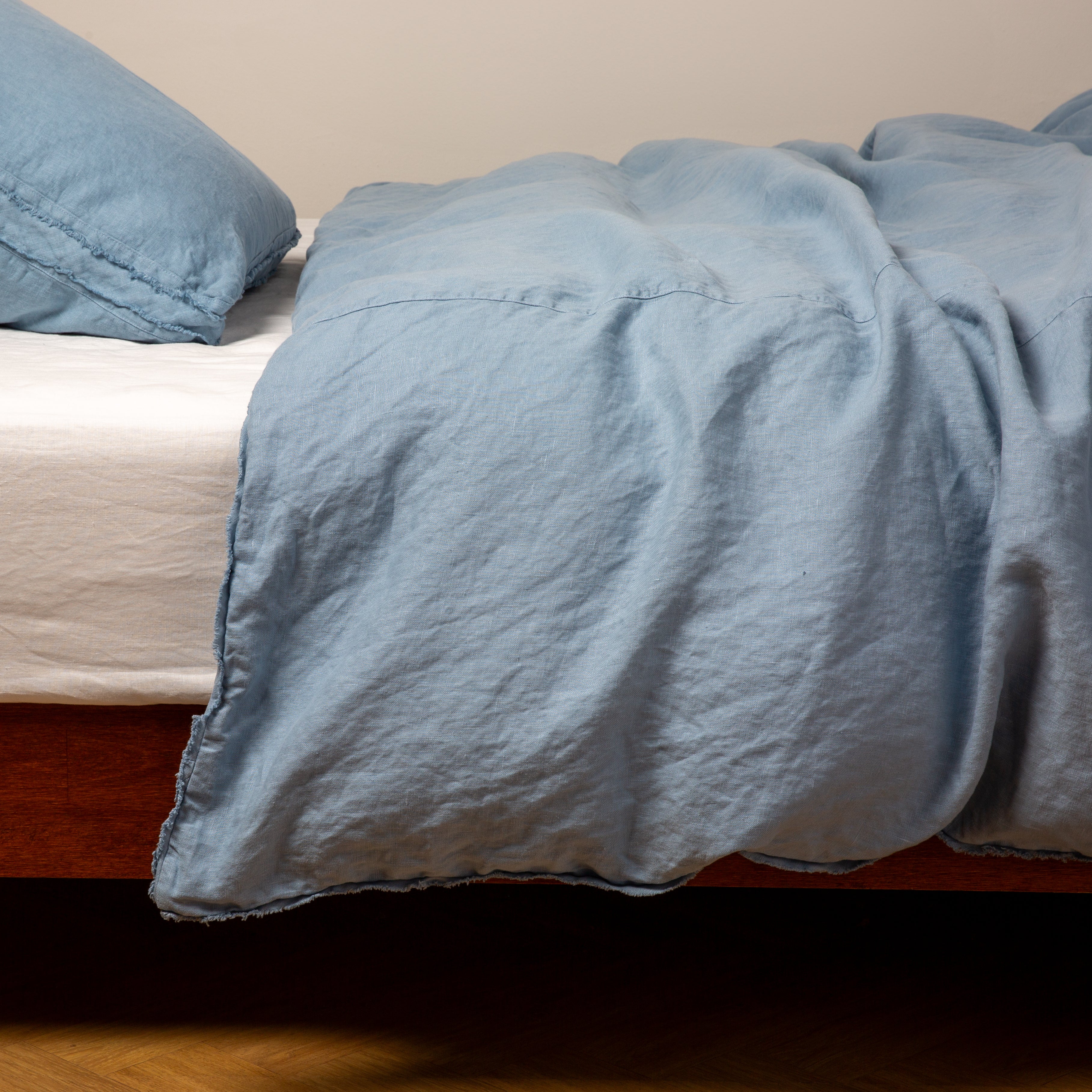 Tahoe Blue: Midweight linen duvet cover in tahoe blue on a bed, side view.