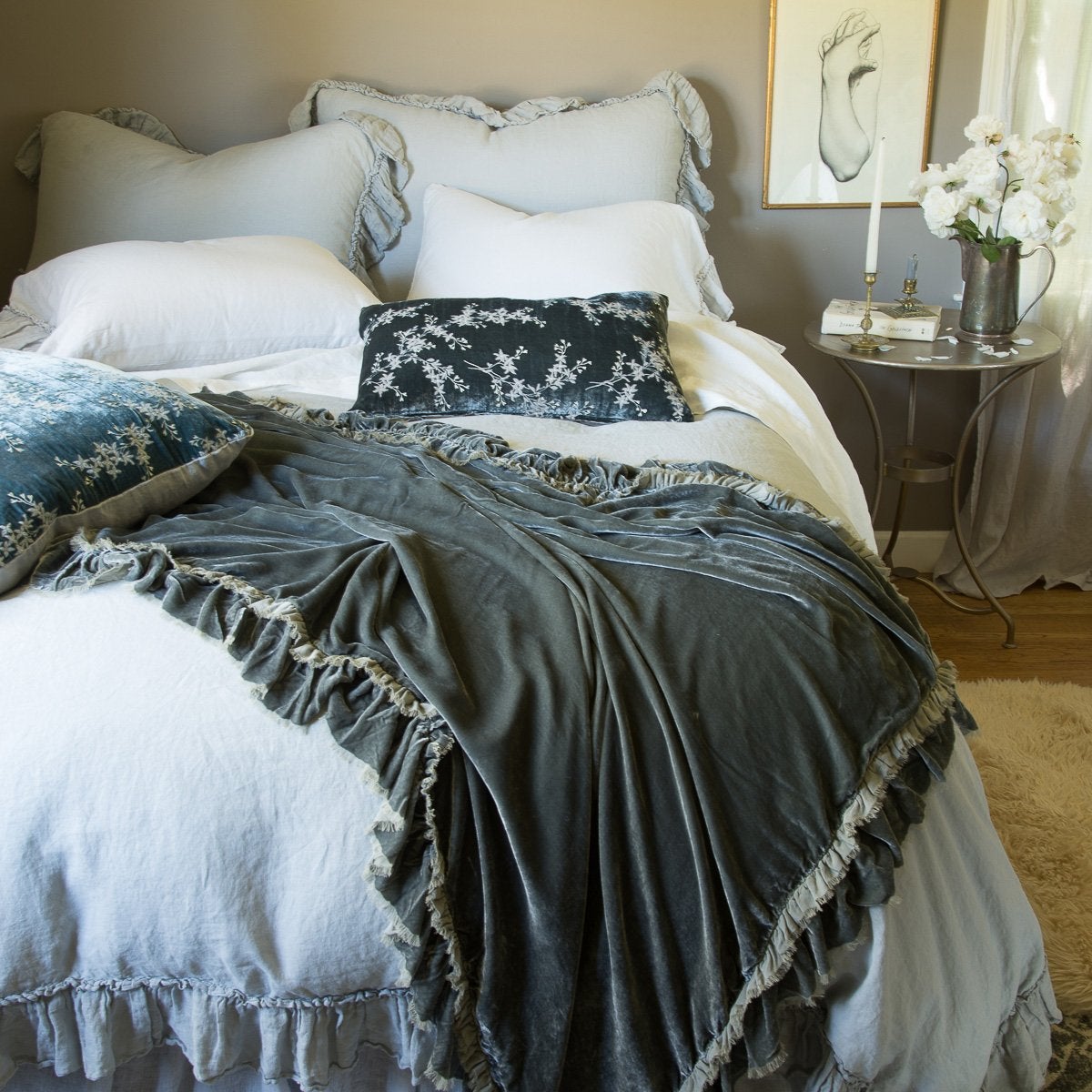 : Linen Whisper shams in mineral, layered with matching duvet cover and richly colored silk velvet accessory pieces - end of bed view.